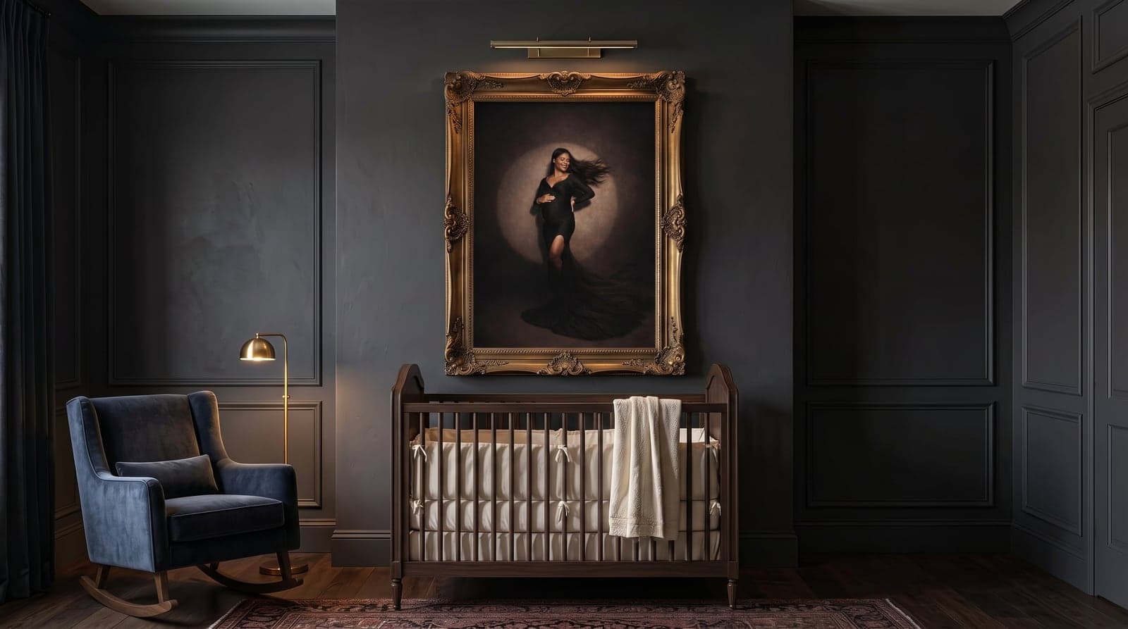 Gold-framed maternity portrait with a picture light above a dark-wood crib in a moody nursery