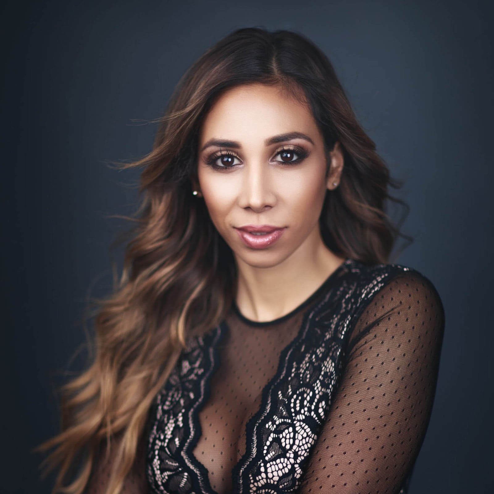 Editorial branding headshot of a woman in a black lace top on a navy background