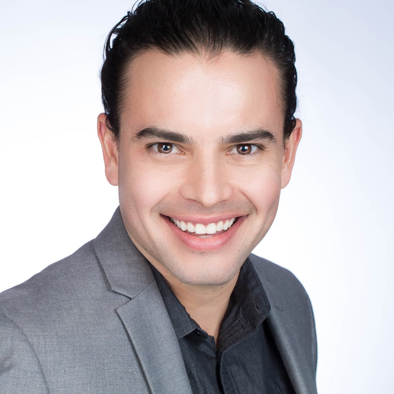 Professional headshot of a smiling man in a grey blazer