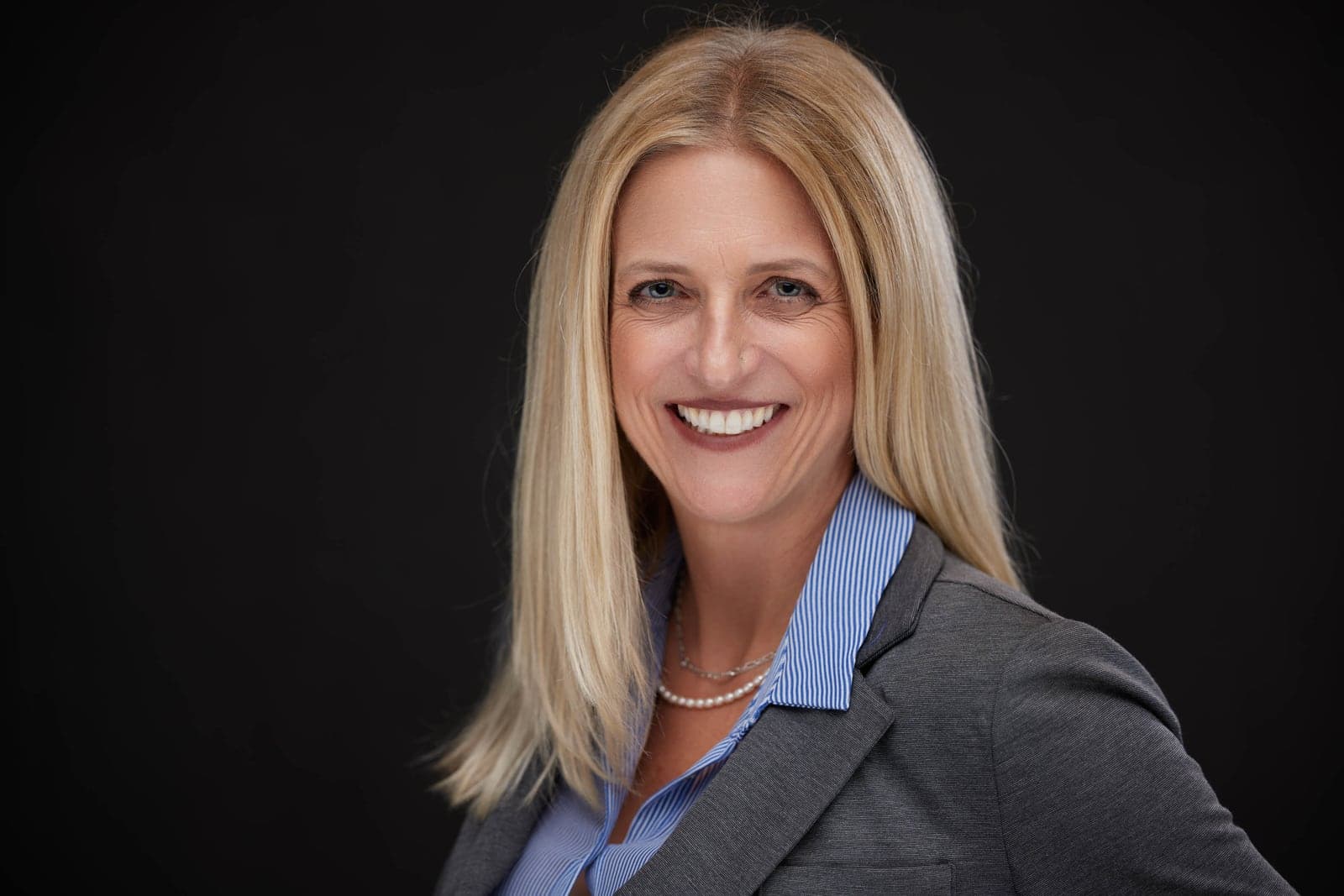 Corporate headshot of a blonde businesswoman in a grey blazer
