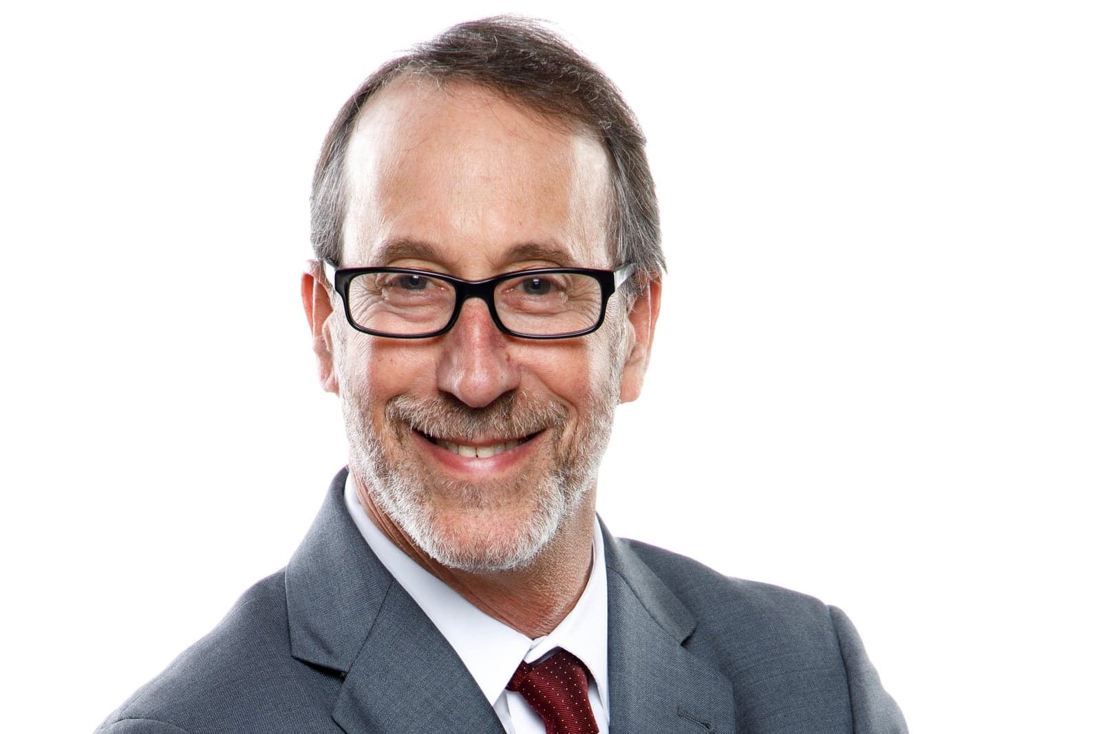 Professional headshot of a man in glasses and a grey suit on a white background