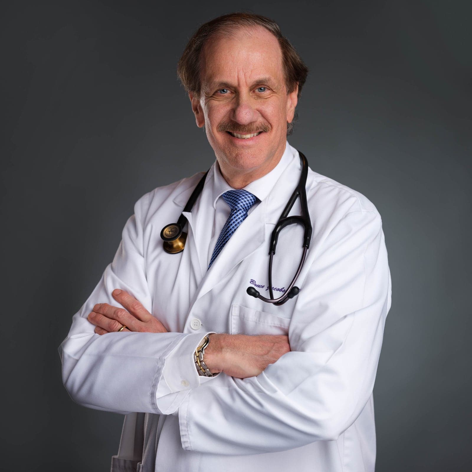 Professional headshot of a doctor in a white coat with a stethoscope