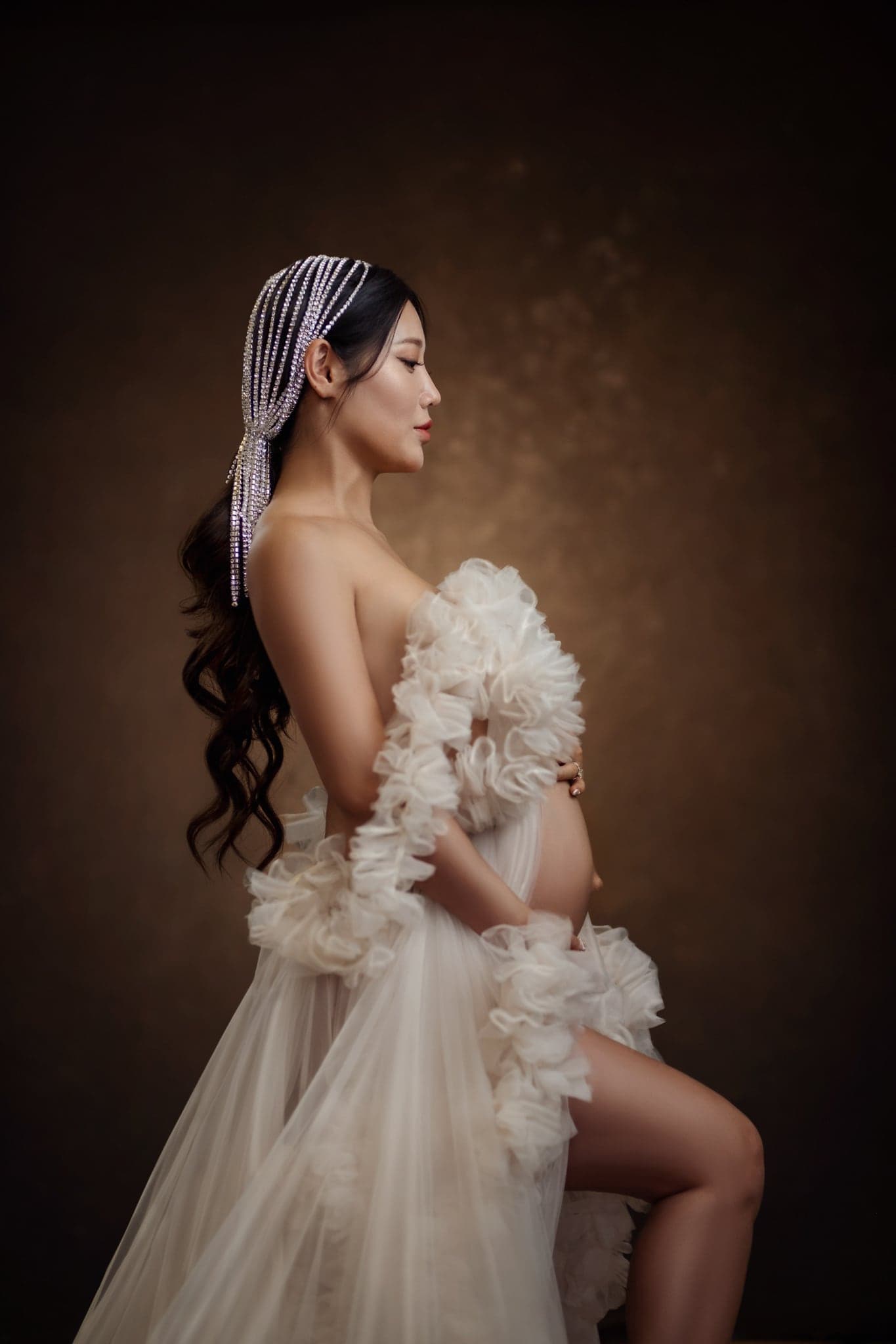 Maternity portrait in an ivory ruffled gown with a veil