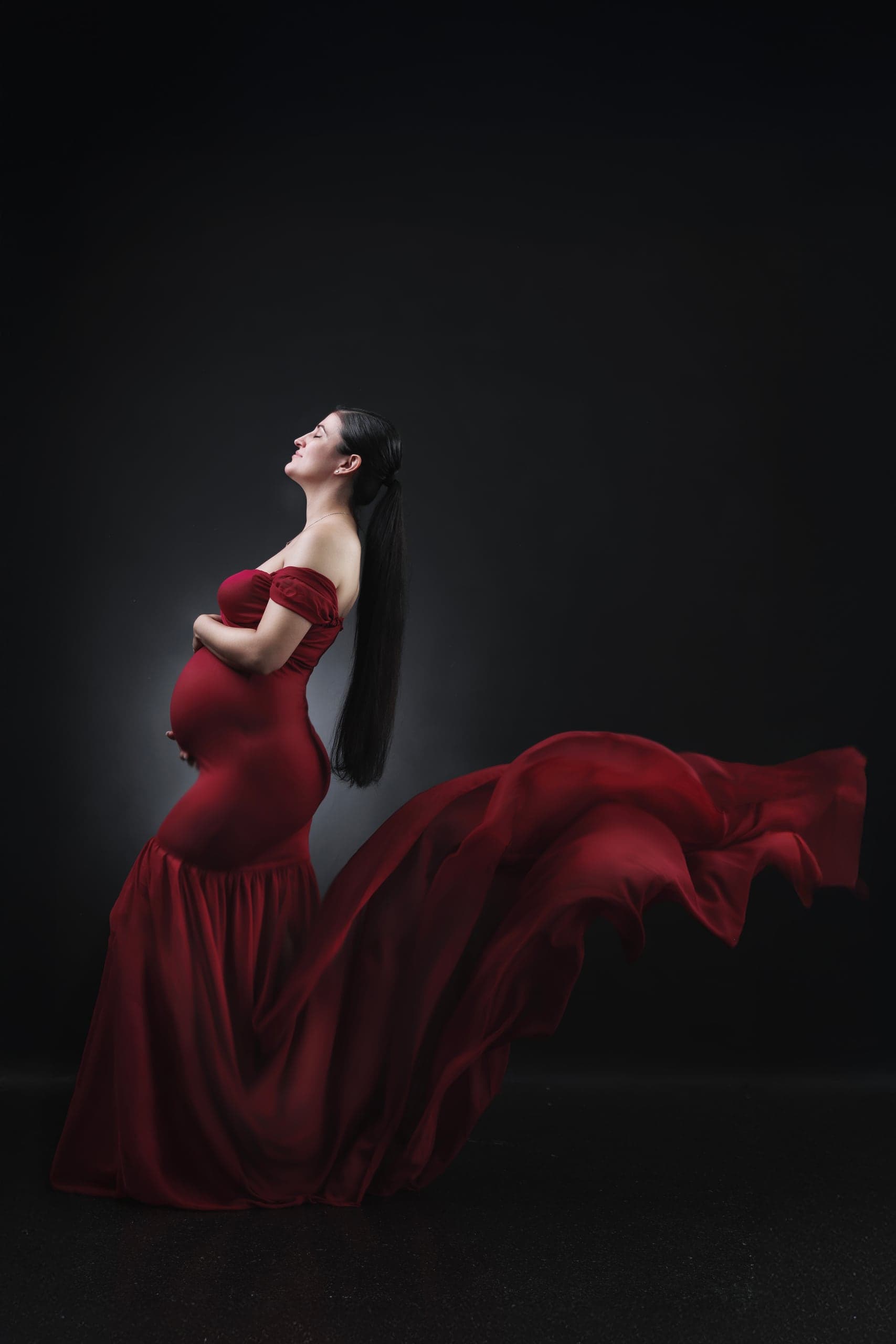 Editorial maternity portrait with red fabric in motion