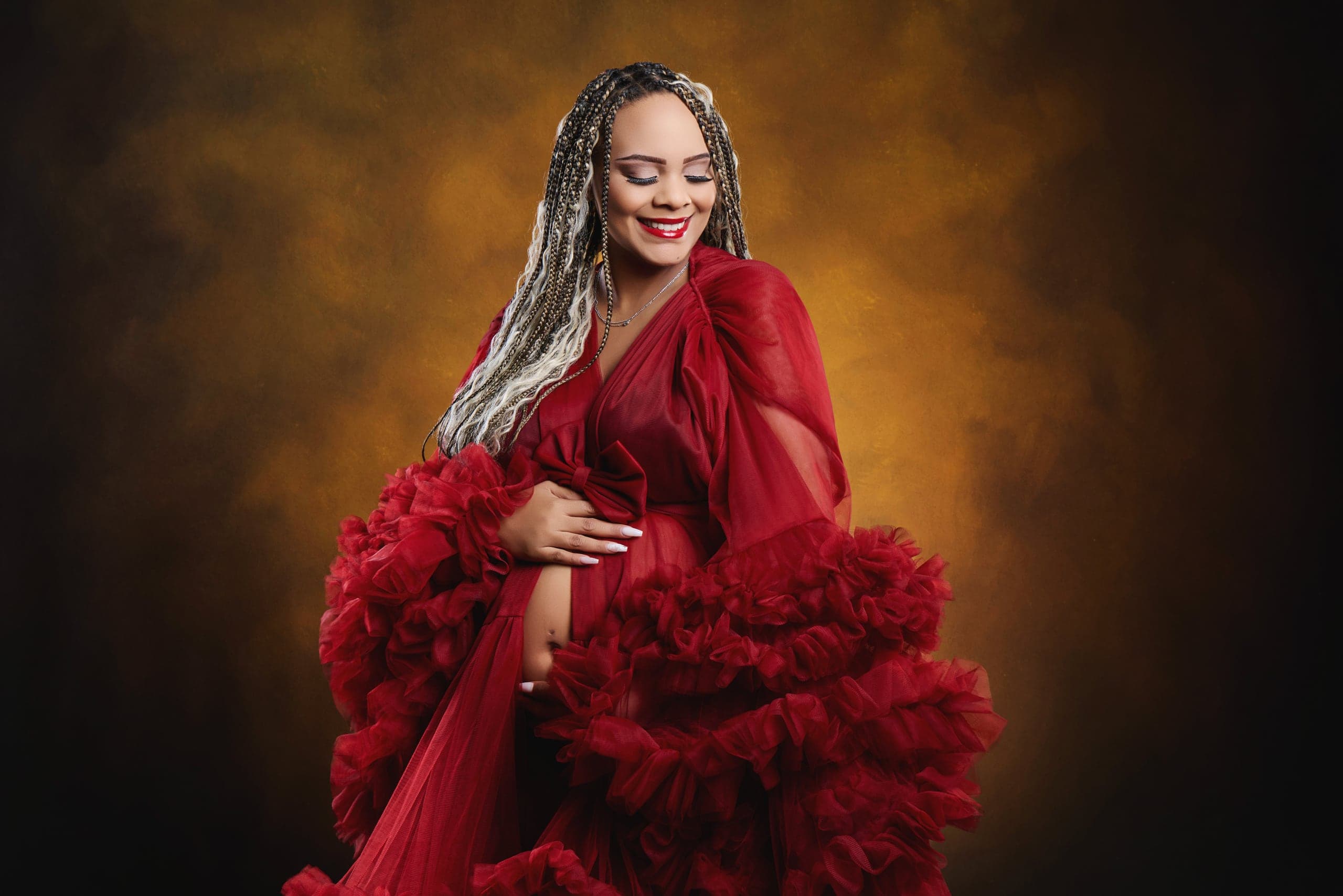 Dramatic maternity portrait in a red ruffled gown