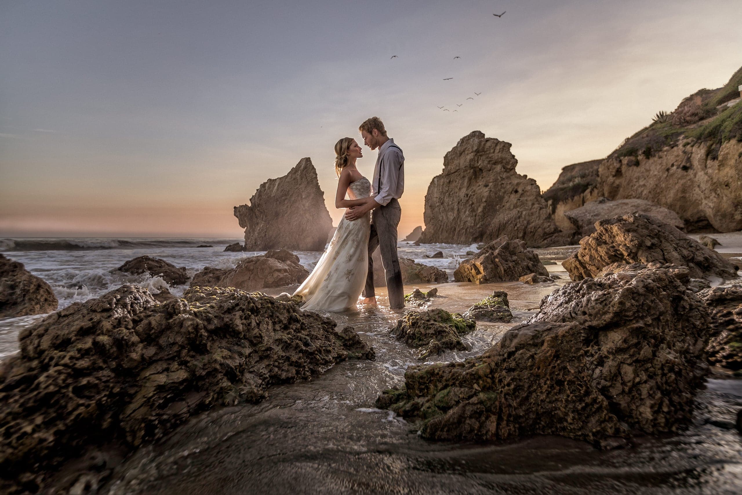 Couple embracing on the rocks at golden hour, El Matador Beach