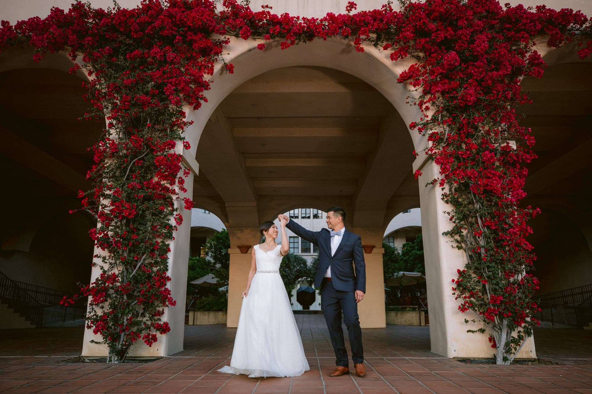 Wedding couple beneath bougainvillea-covered arches