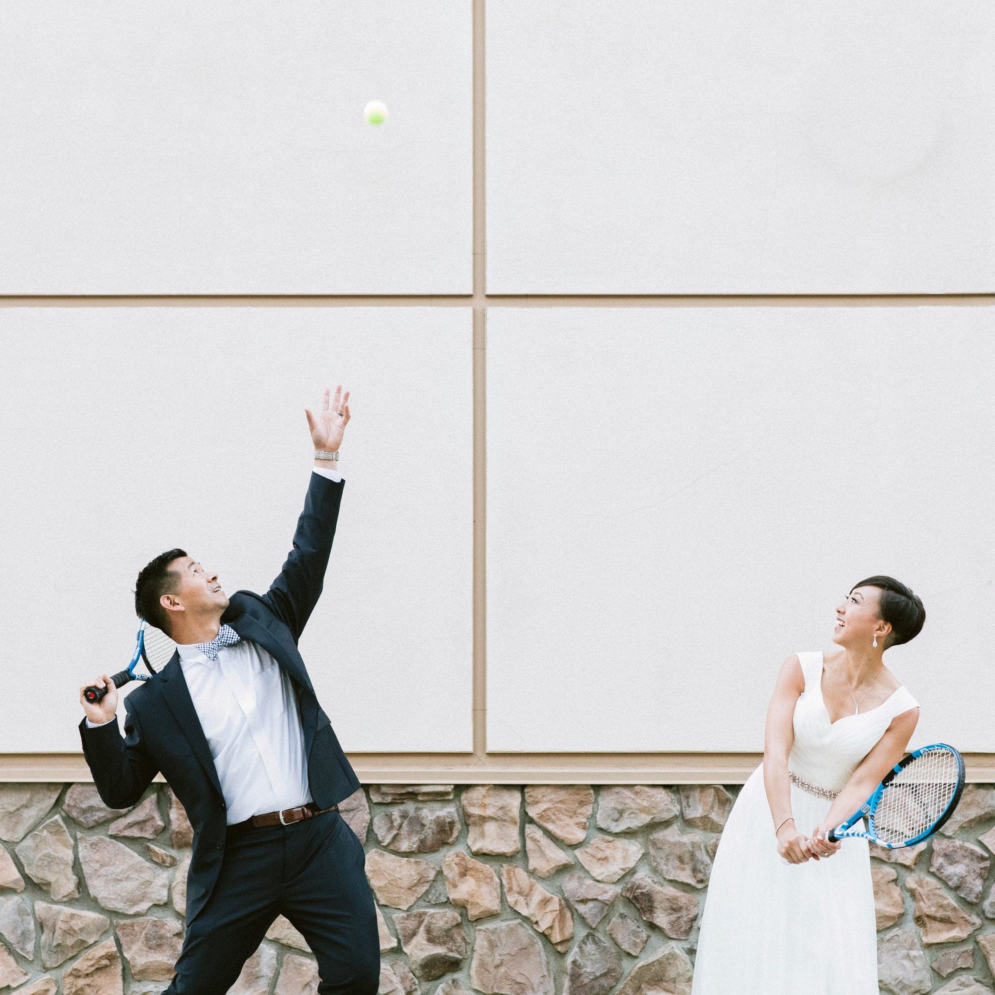 Playful wedding portrait against a white geometric wall