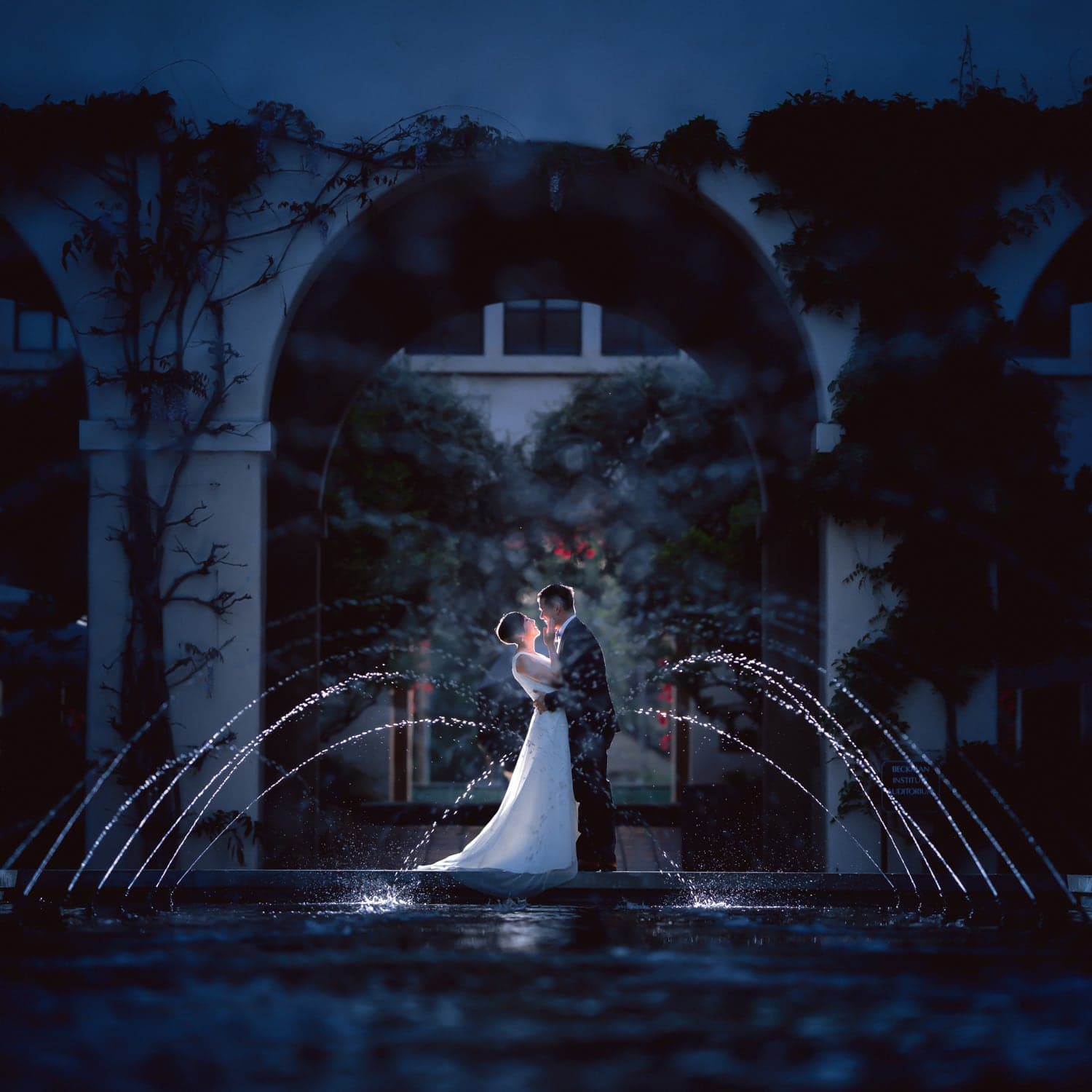 Wedding couple beside an illuminated fountain at night
