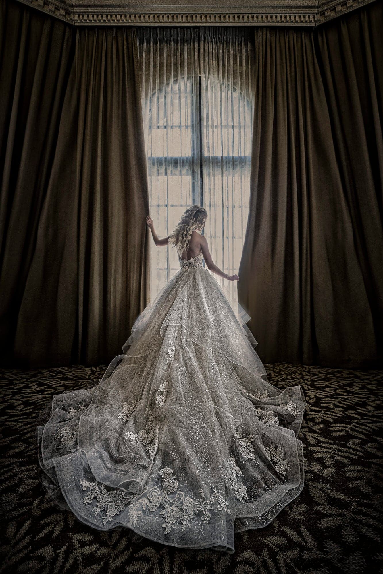 Bride in her gown beside a tall Mission Inn window