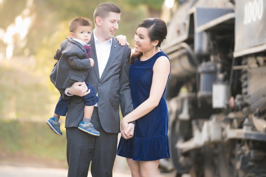 Bride and groom posed beside a weathered vintage green locomotive in the open-air train yard at Travel Town Museum in Griffith Park.