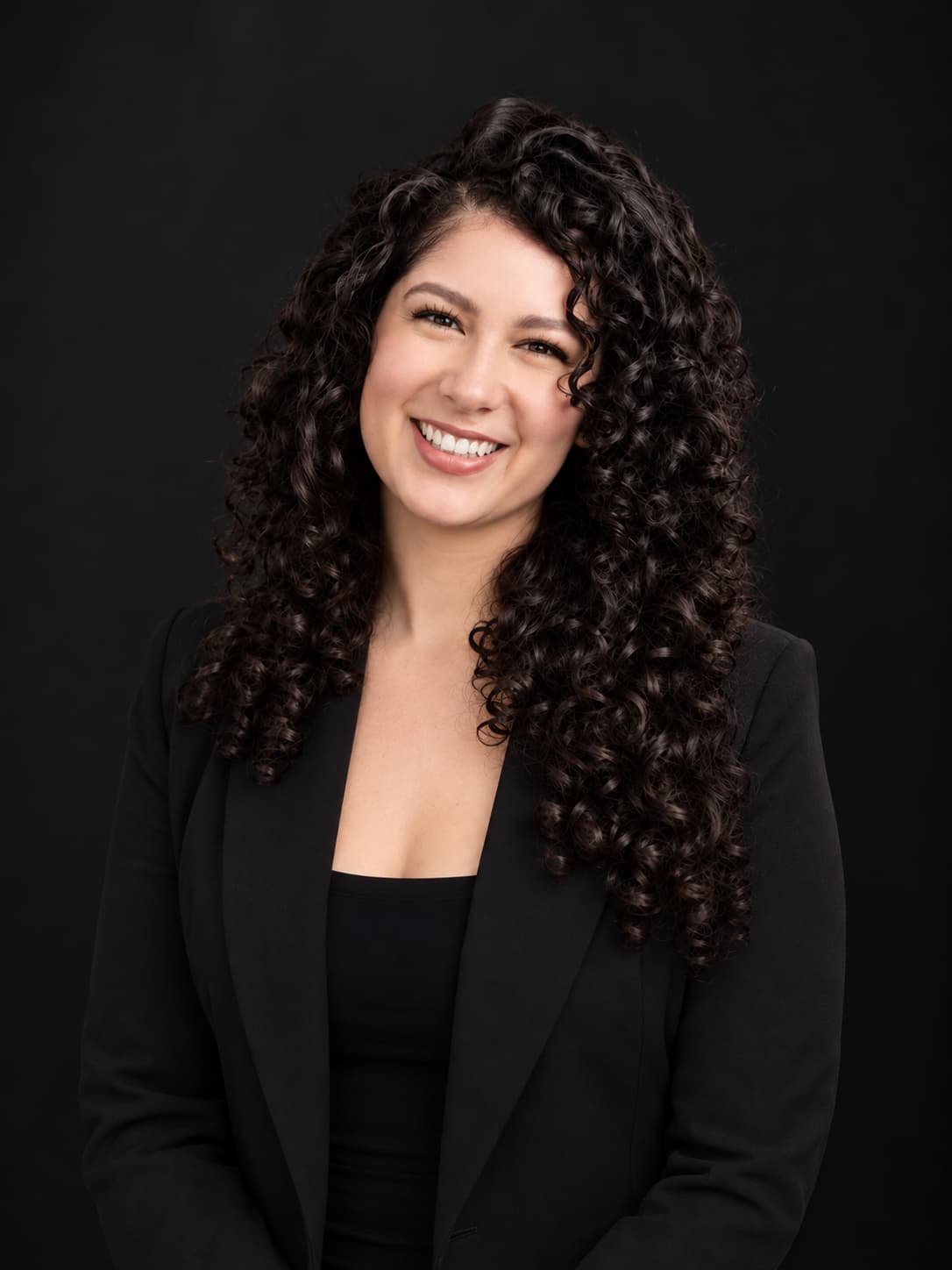 Courtney in a black blazer against a dark studio backdrop