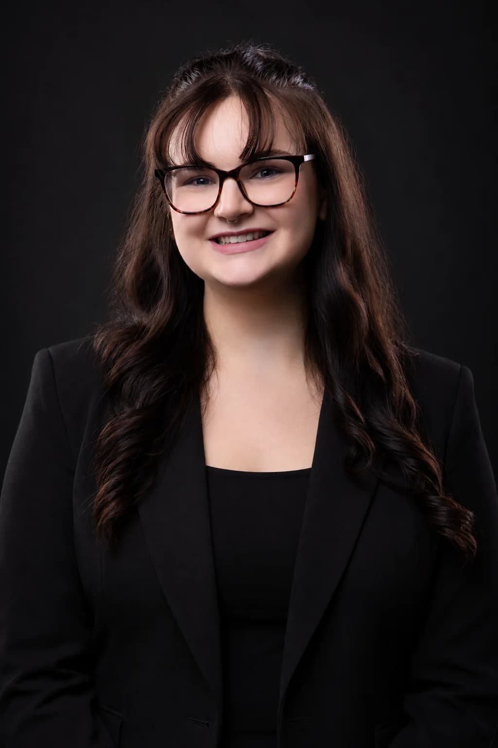 Ryleigh in a black blazer against a dark studio backdrop