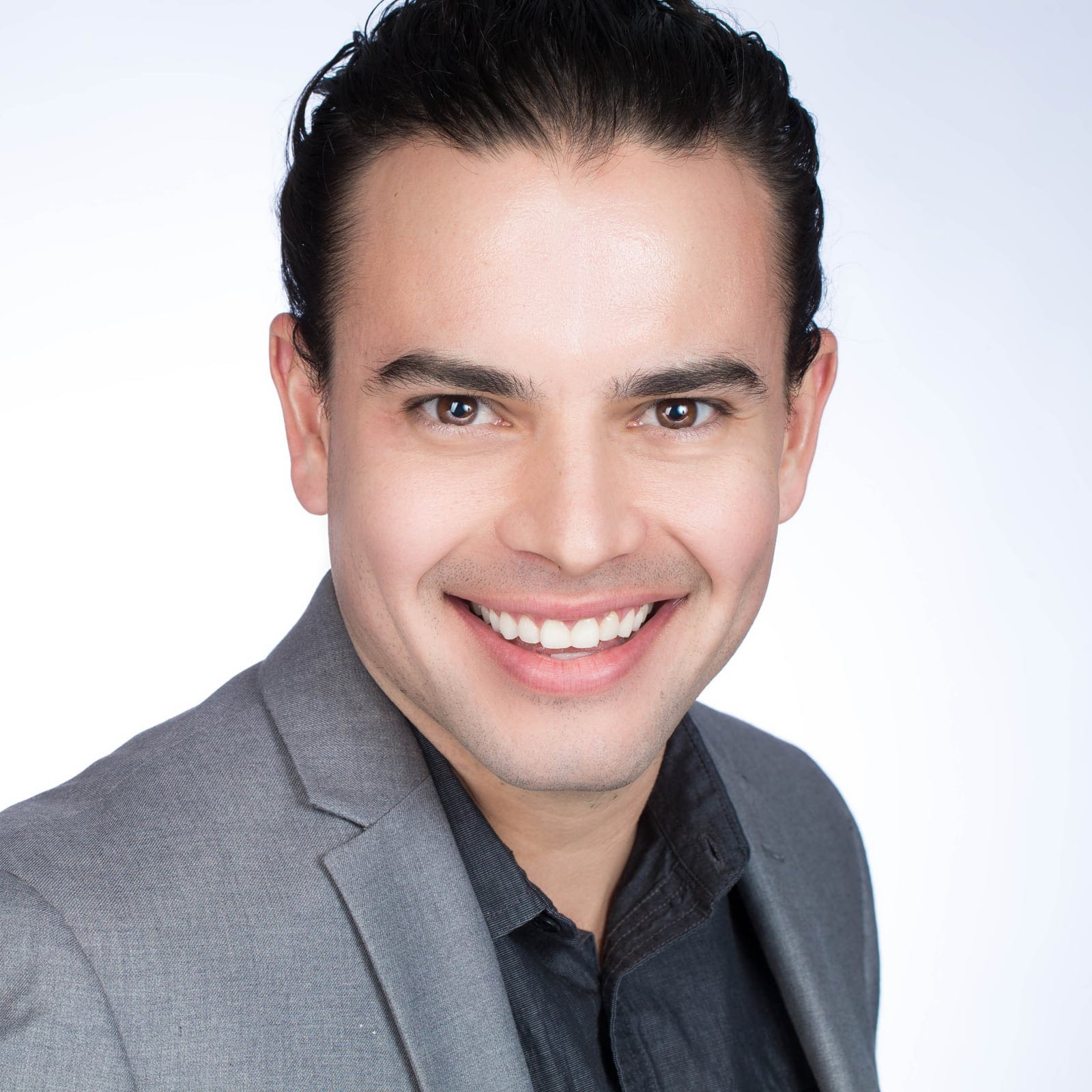 Professional headshot of a smiling man in a grey blazer
