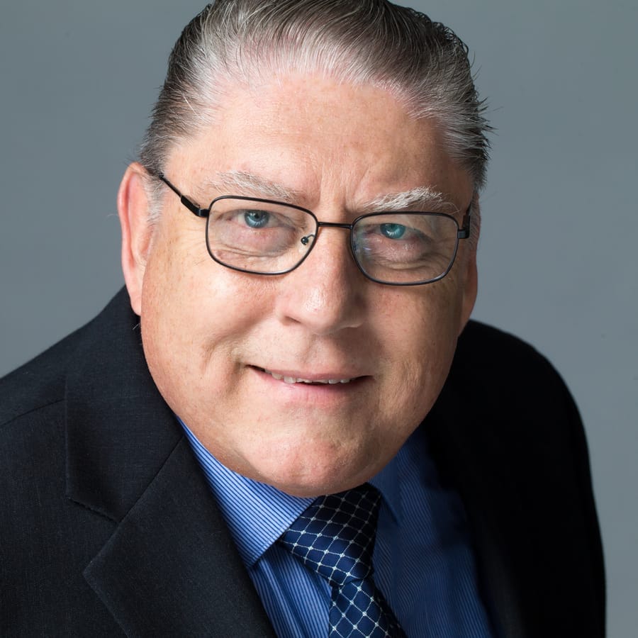 Executive headshot of a senior businessman in a suit on a grey studio backdrop
