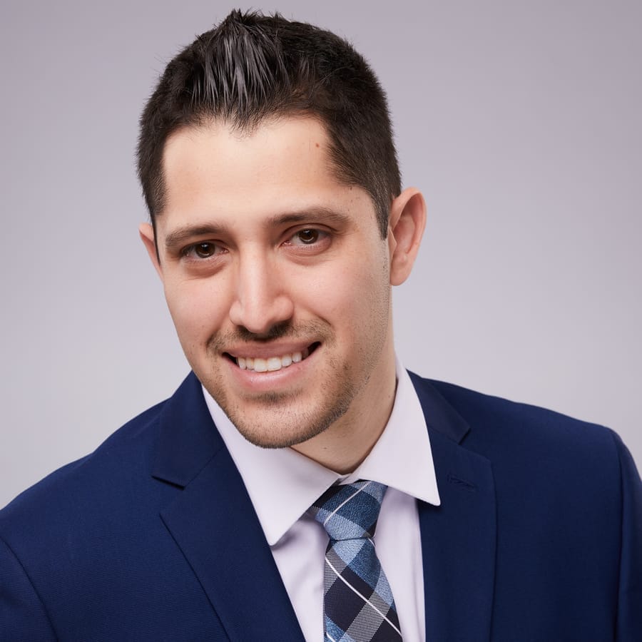 Professional headshot of a young businessman in a navy suit