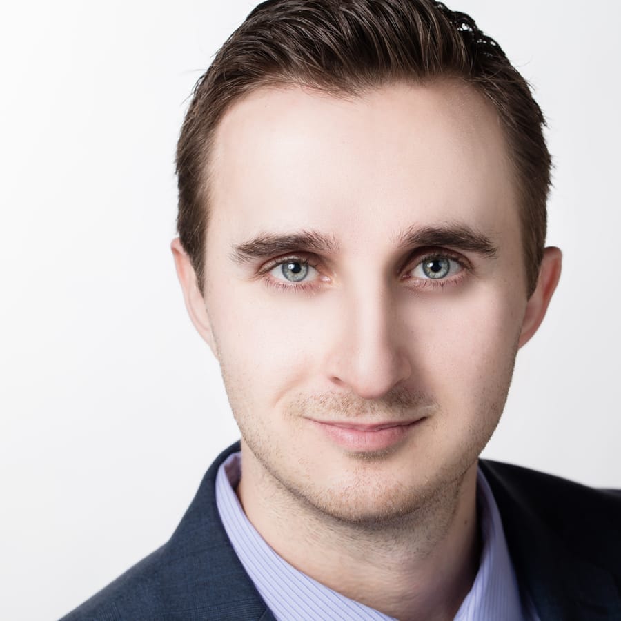 Professional headshot of a young man in a suit and tie