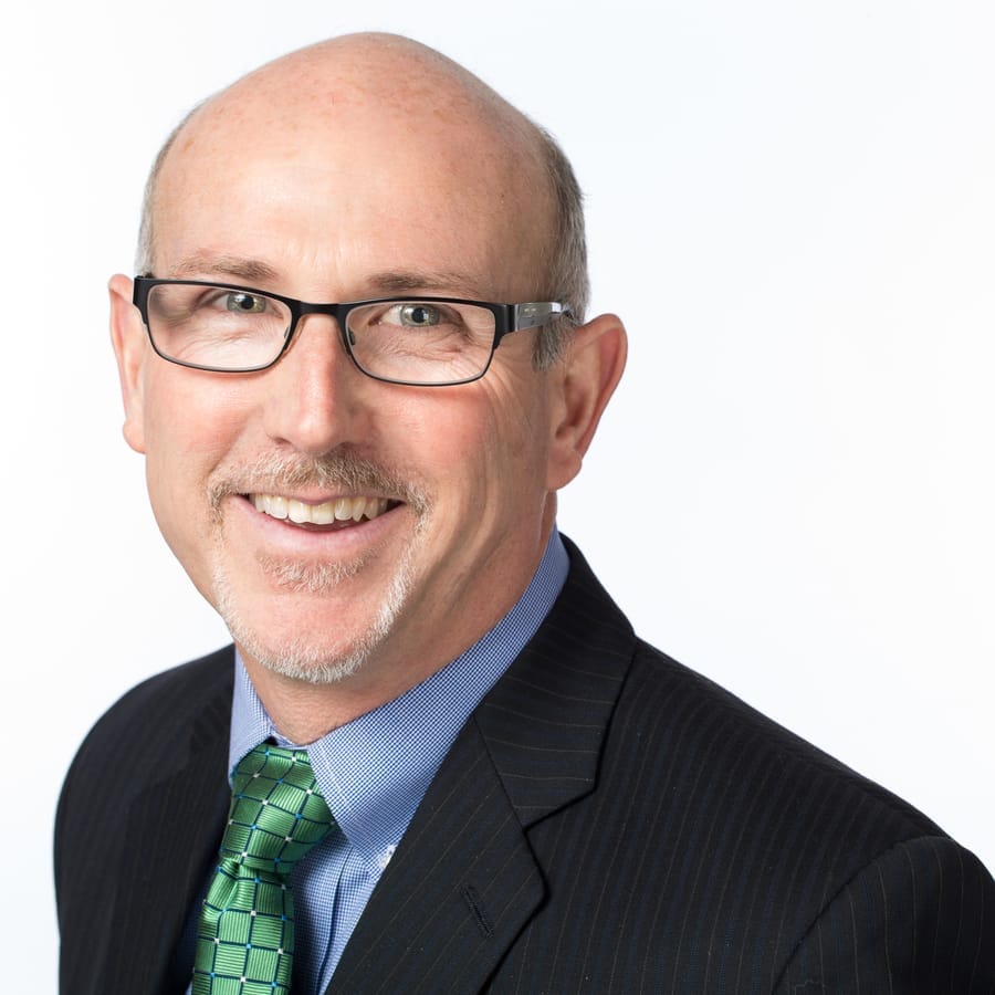 Corporate headshot of a man in glasses and a green tie