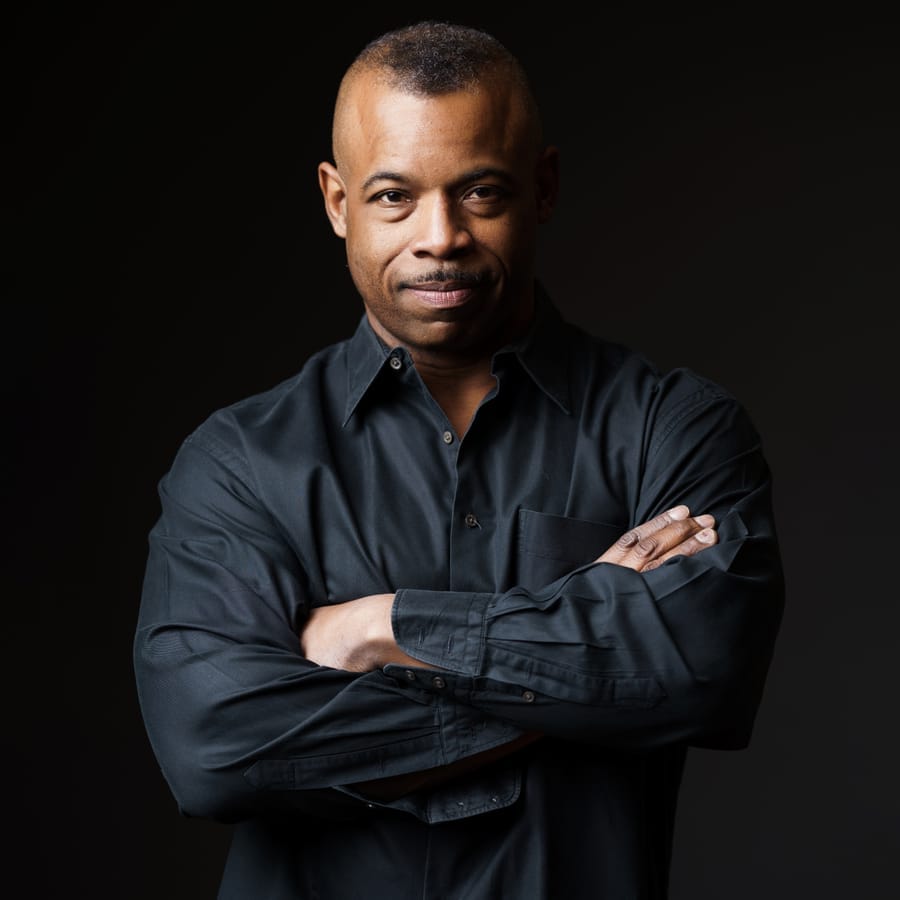 Dramatic executive headshot of a man with arms crossed on a dark backdrop