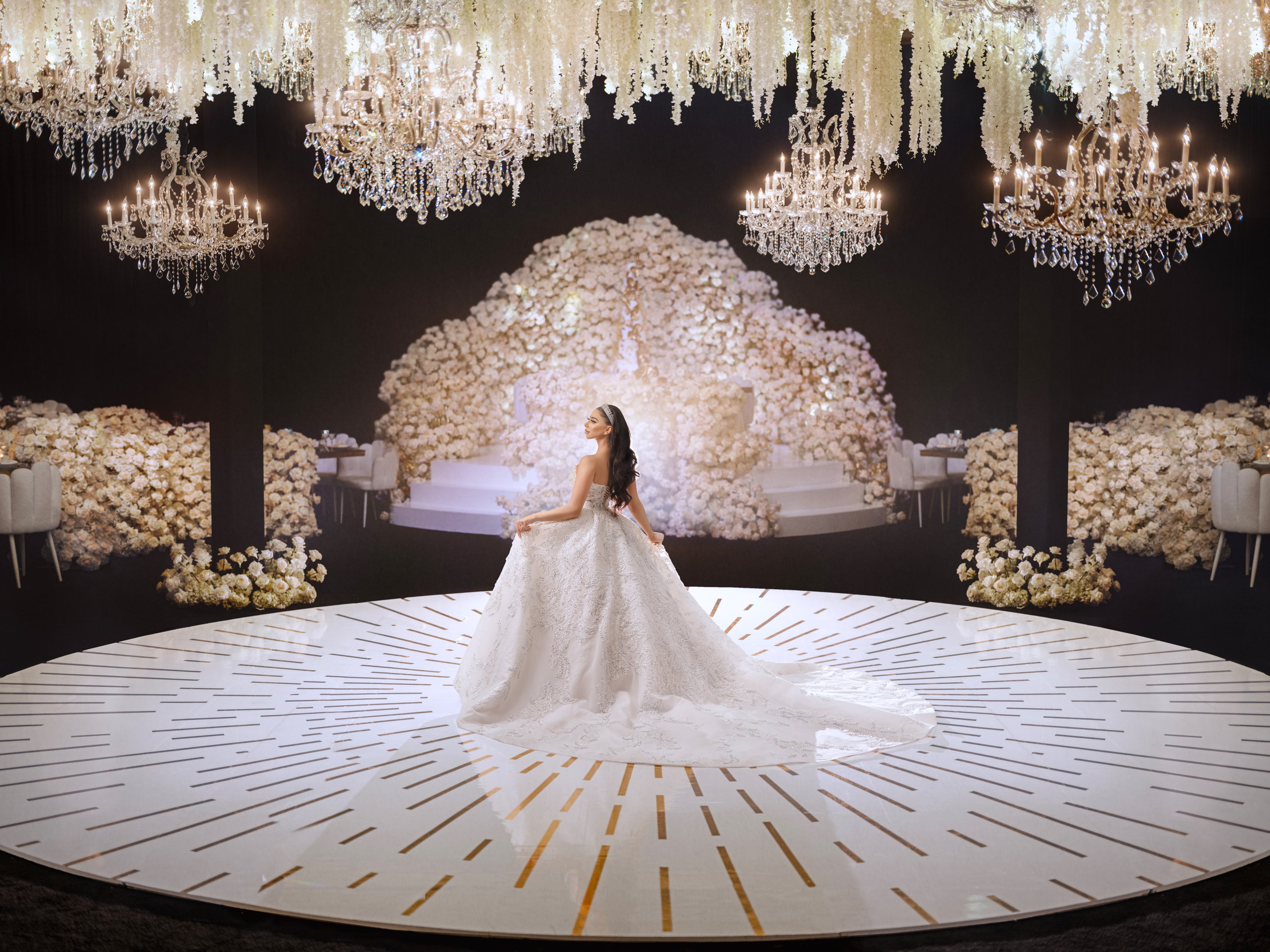 Bride standing beneath chandeliers in an elegant ballroom
