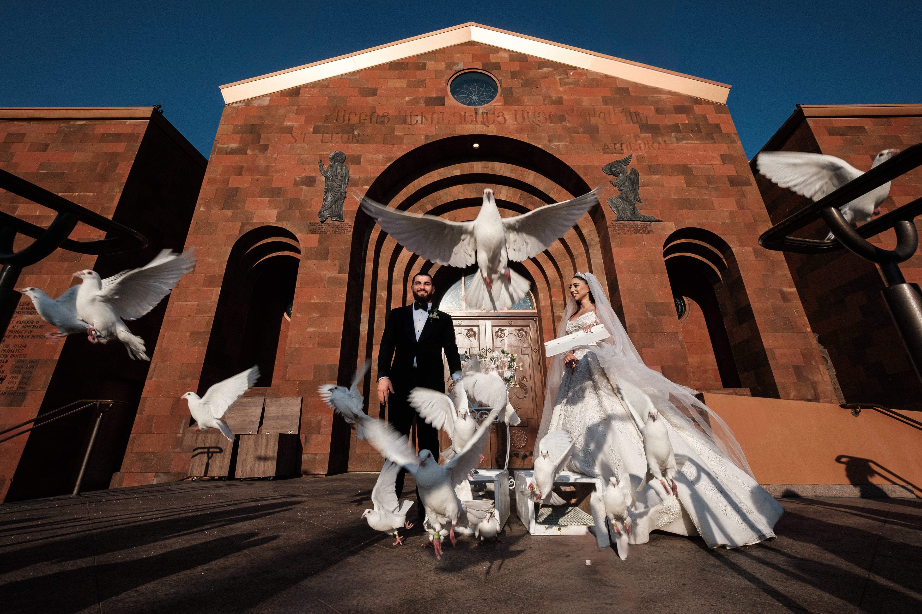 Newlyweds celebrating outside a church as white birds take flight