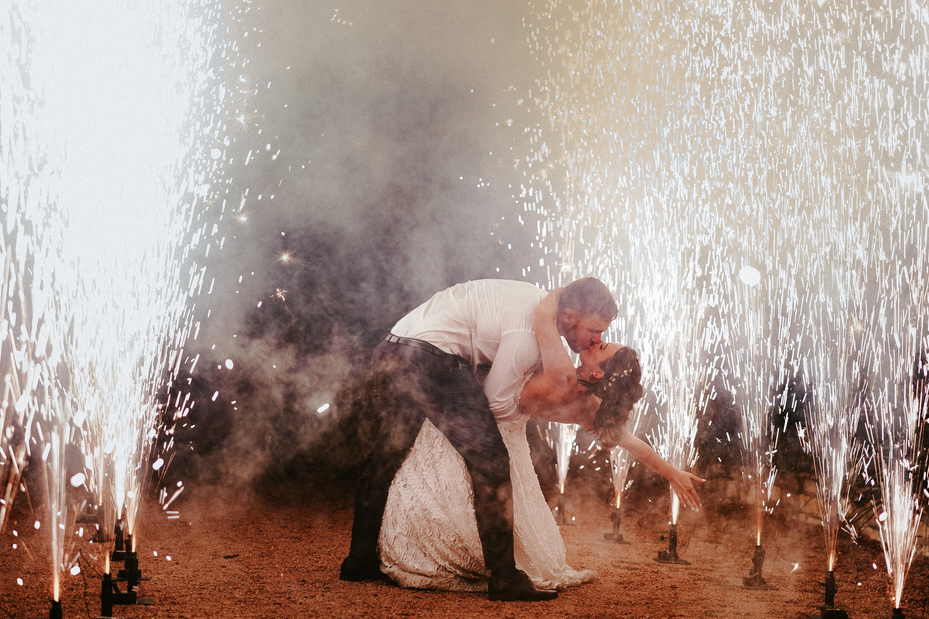 Newlyweds kissing beneath a curtain of sparkling water