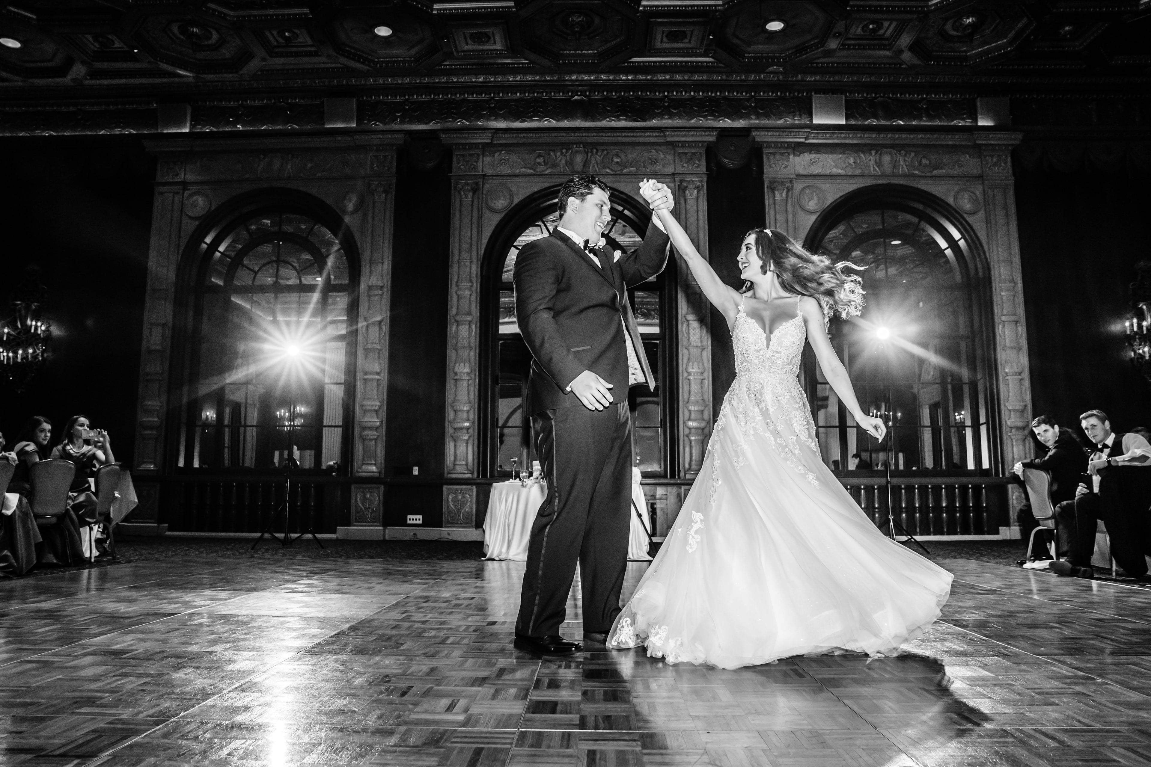 Newlyweds dancing in black and white beneath grand architecture
