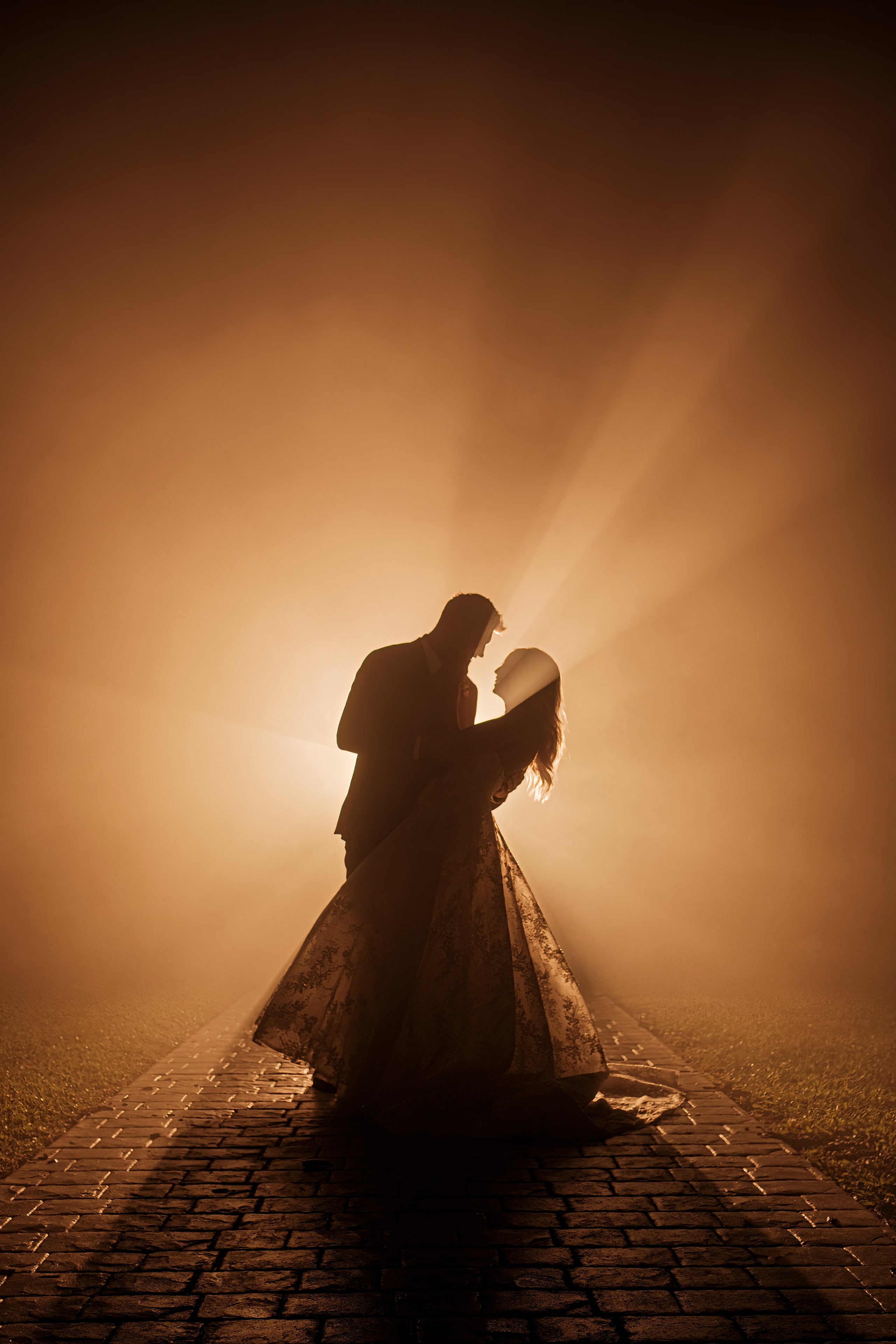 Newlyweds embracing in a dramatic beam of evening light