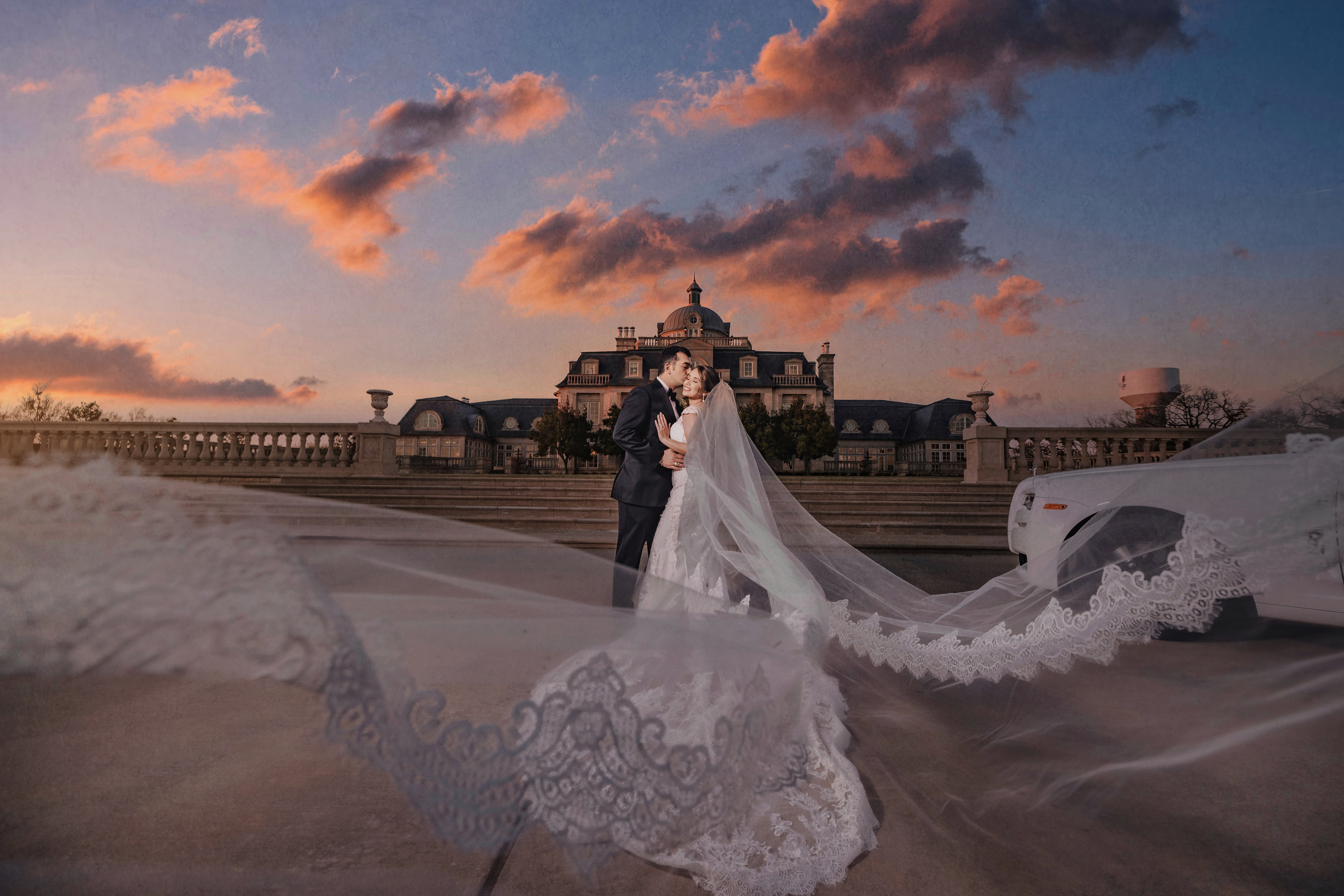 Bride and groom on the Olana terrace beneath a vivid sunset sky