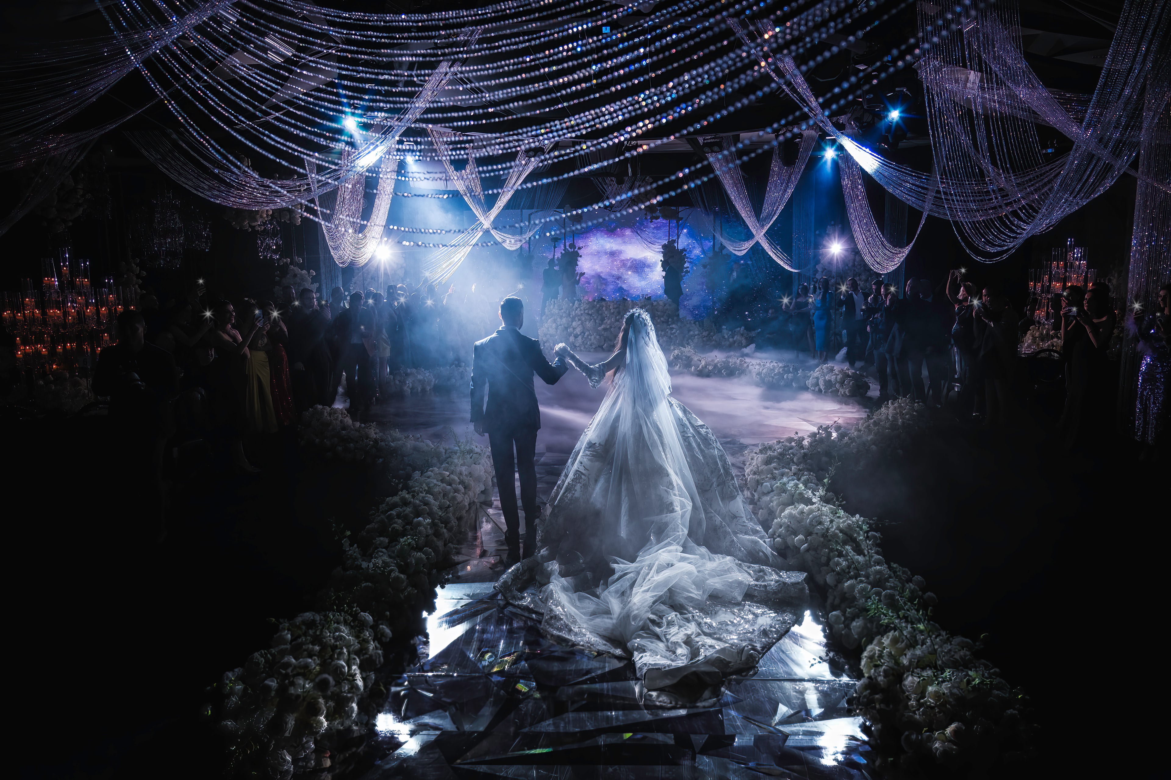 Newlyweds dancing beneath sweeping reception lights