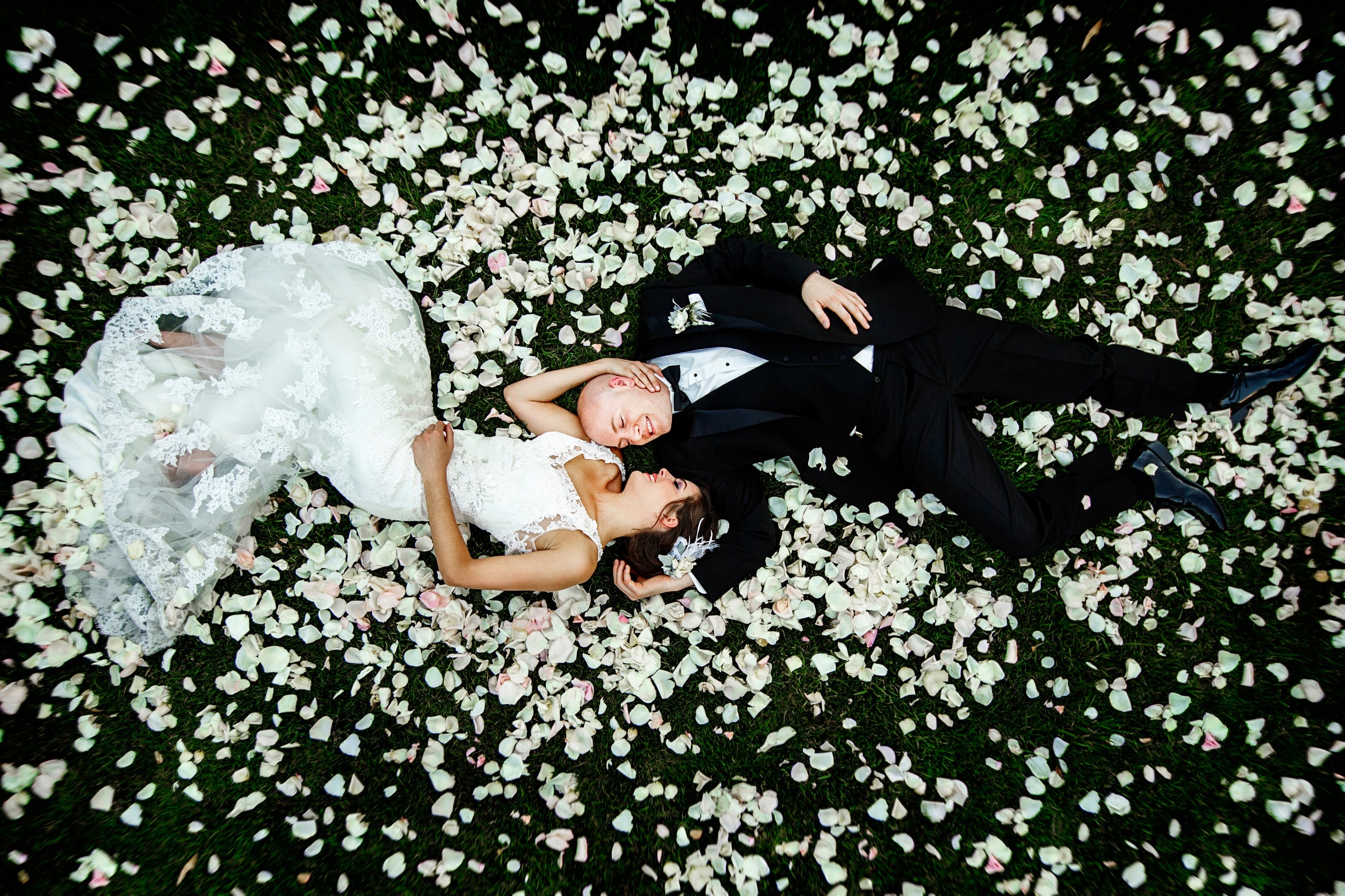 A newlywed couple photographed from above among flower petals