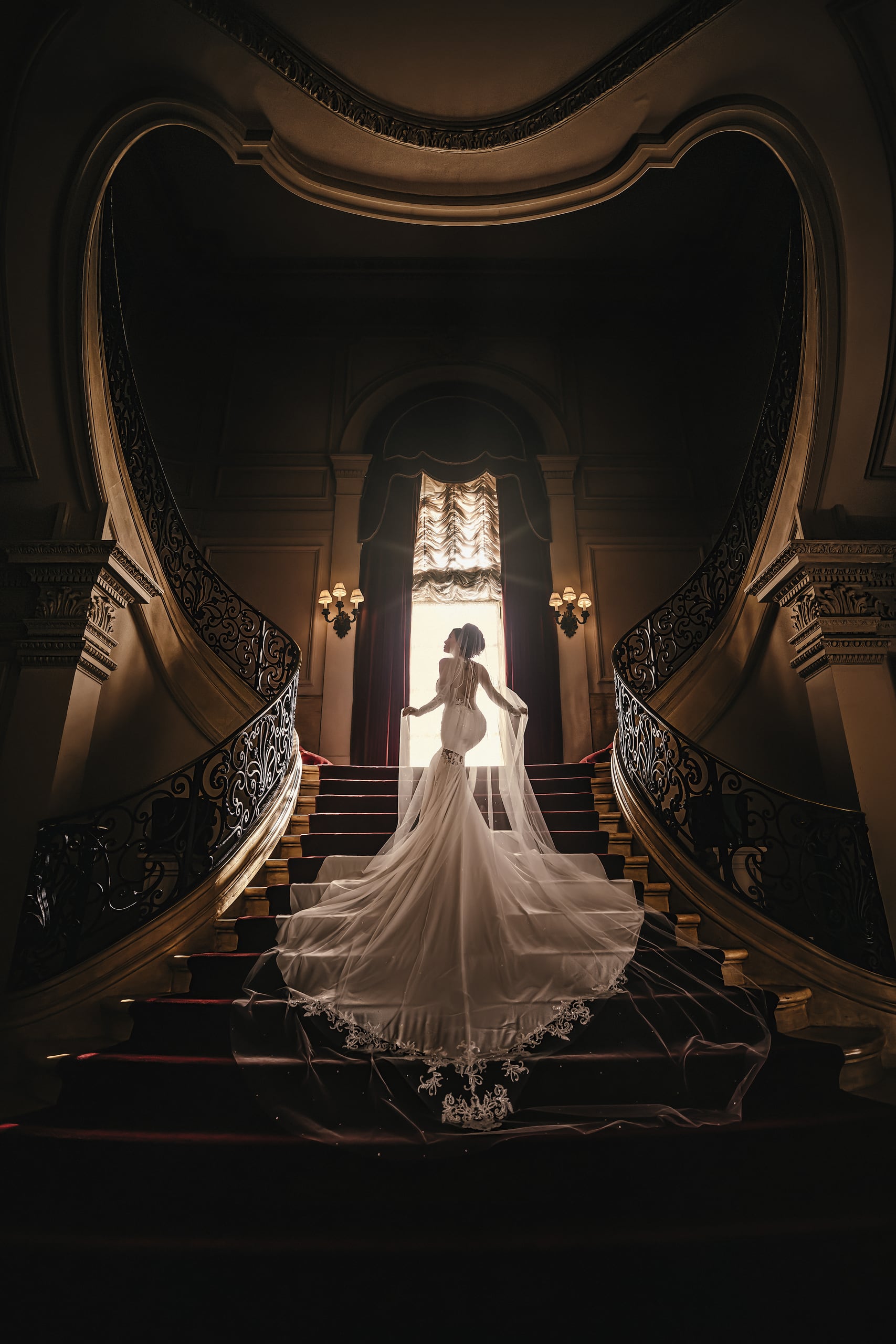 A bride on a grand staircase in stained glass light