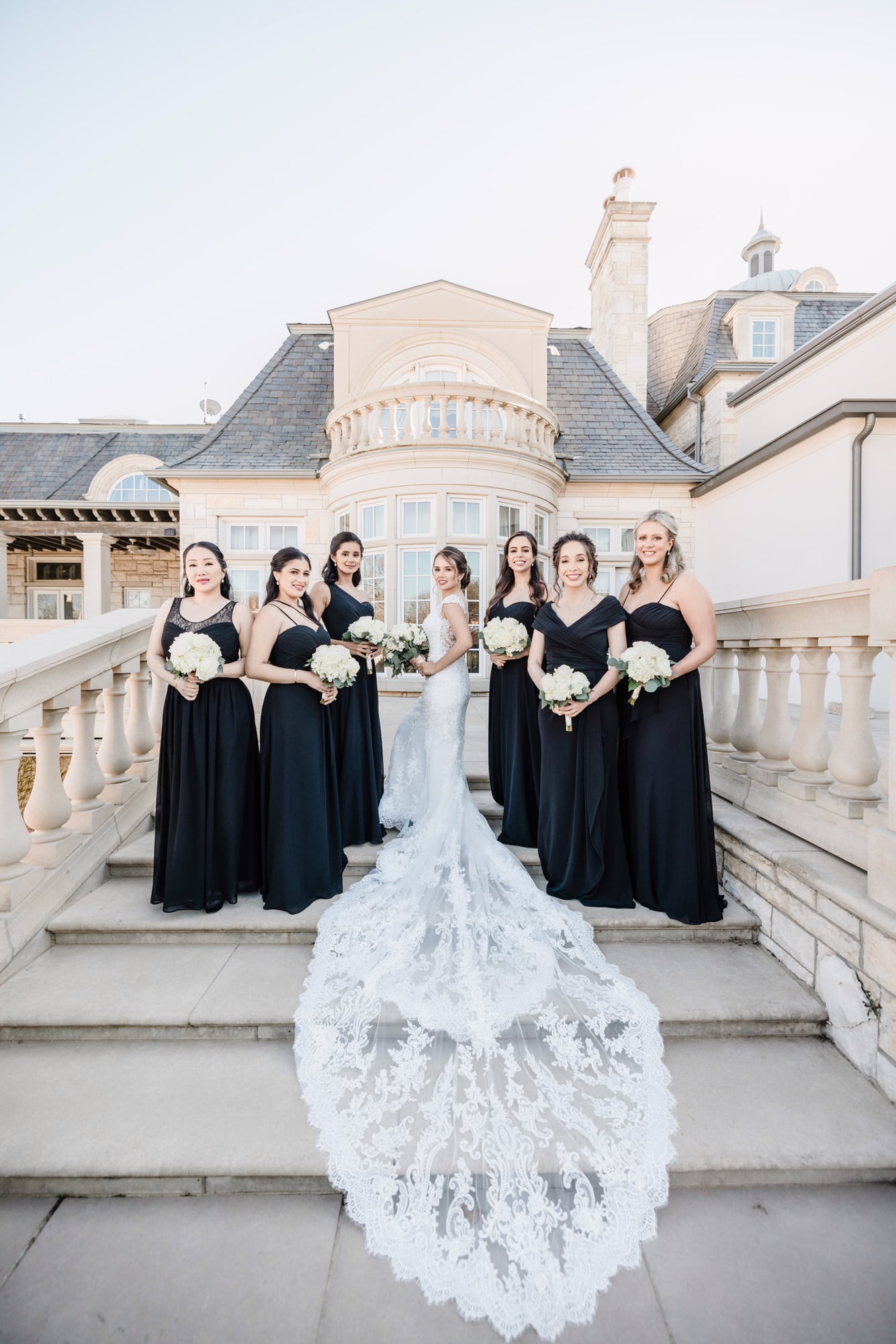 A bride and her bridesmaids on the grand exterior staircase at The Olana in North Texas
