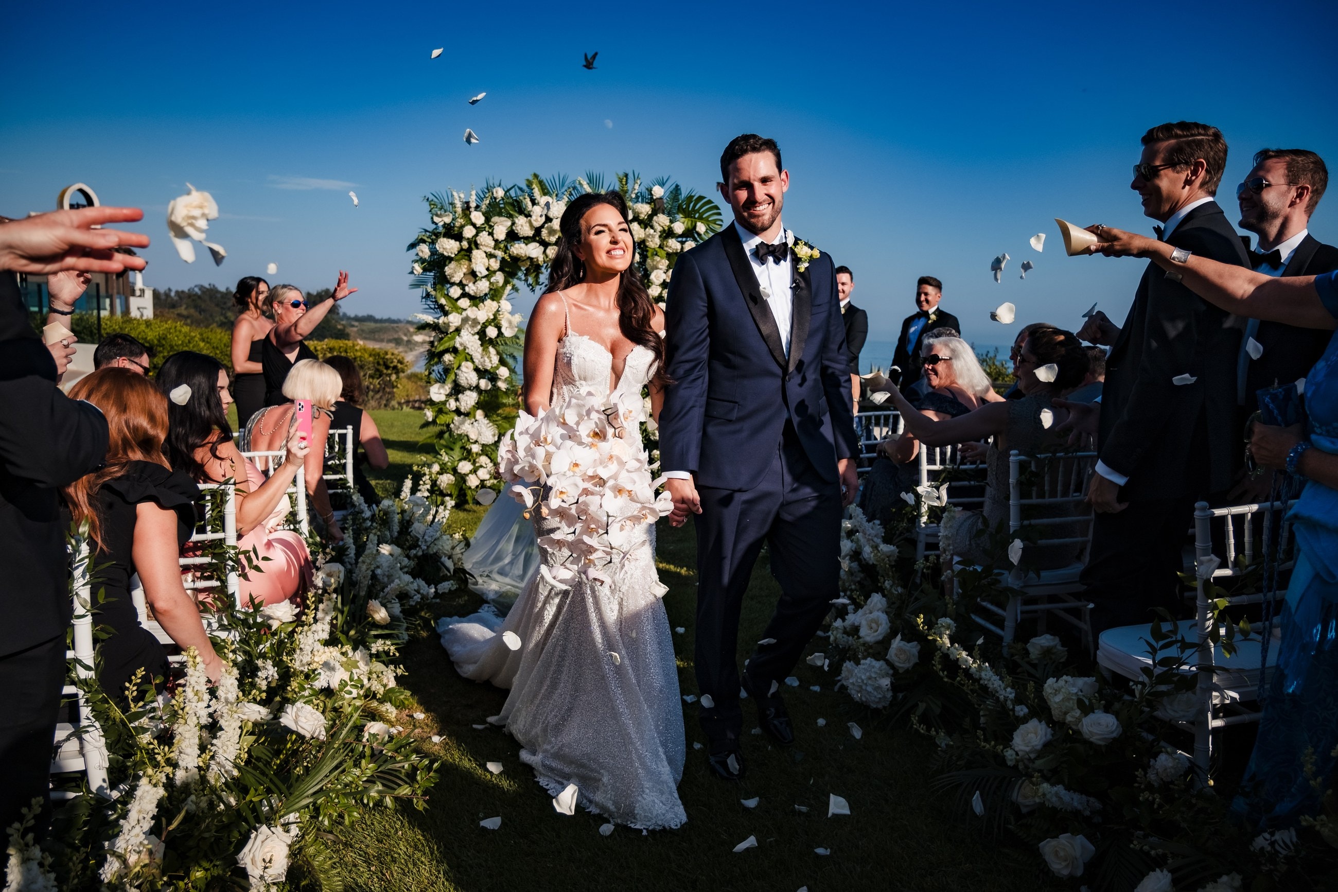 A bride and groom walking back up the aisle as their guests celebrate