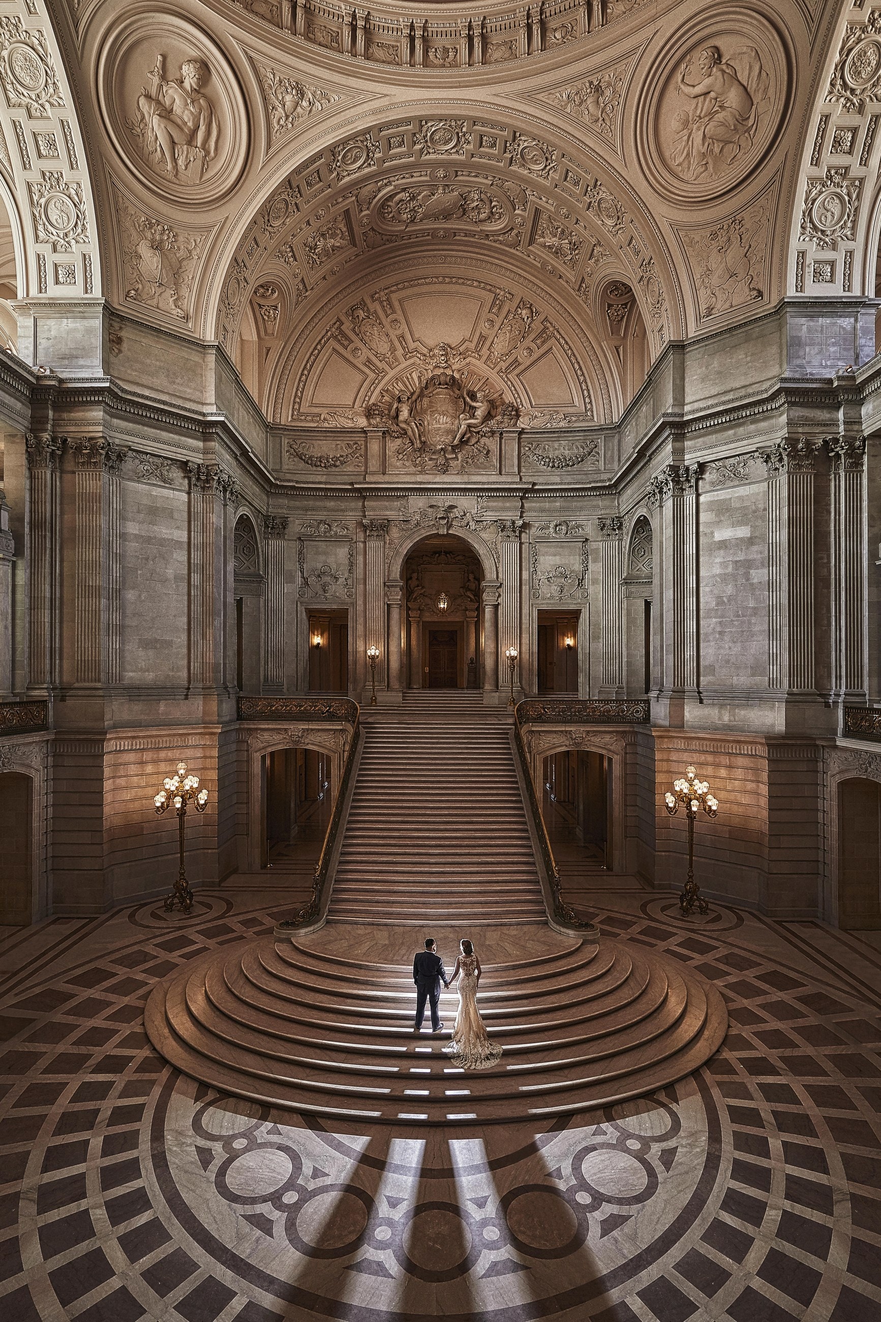 A wedding couple standing on the grand staircase at San Francisco City Hall