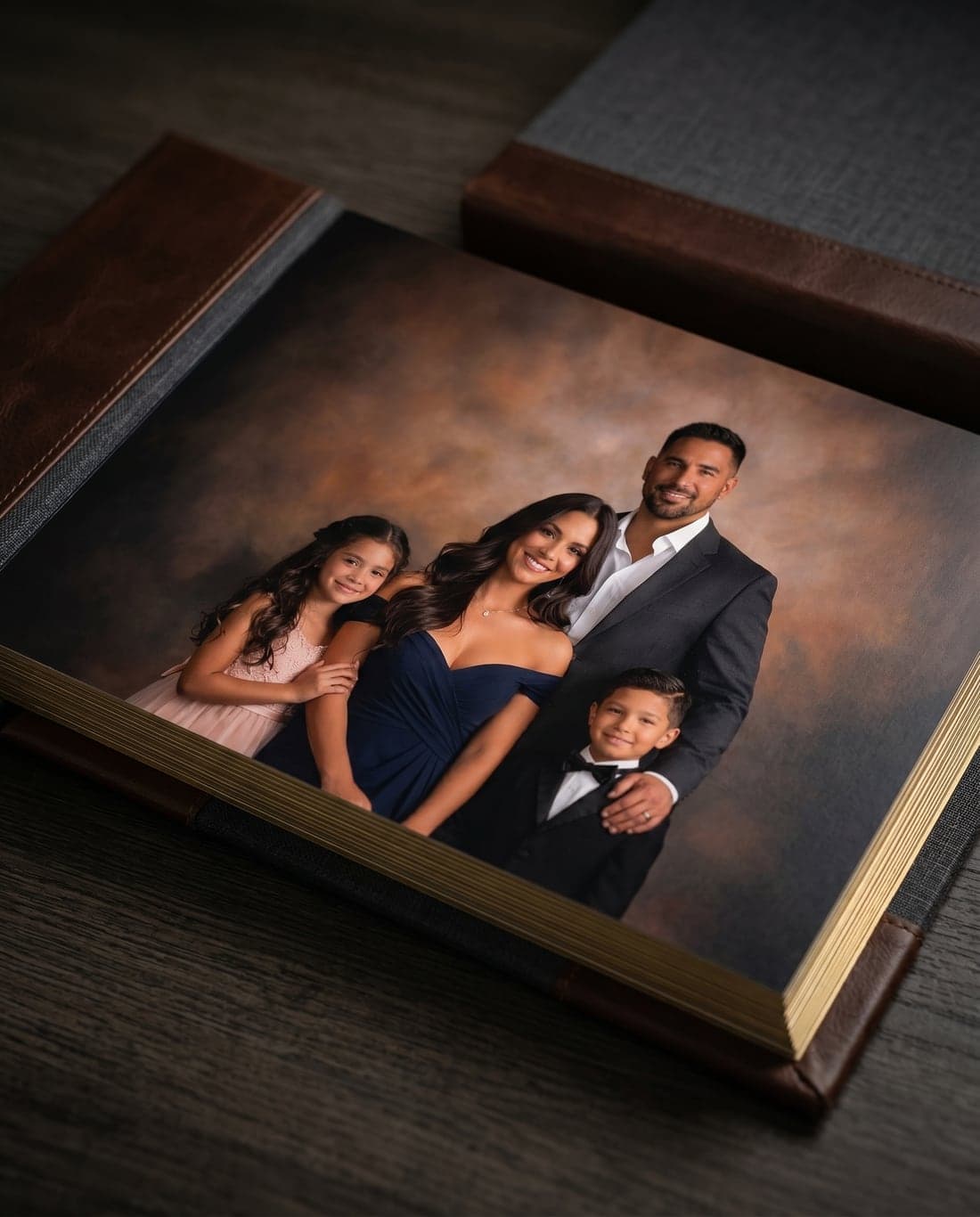 An open heirloom album with a fine-art family portrait spread