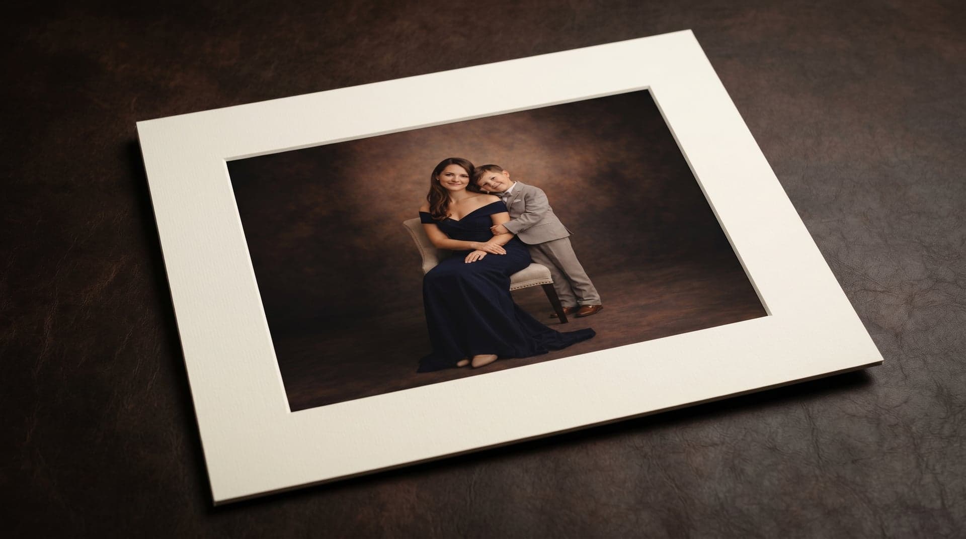 A museum-matted portrait of a mother and son resting on dark leather