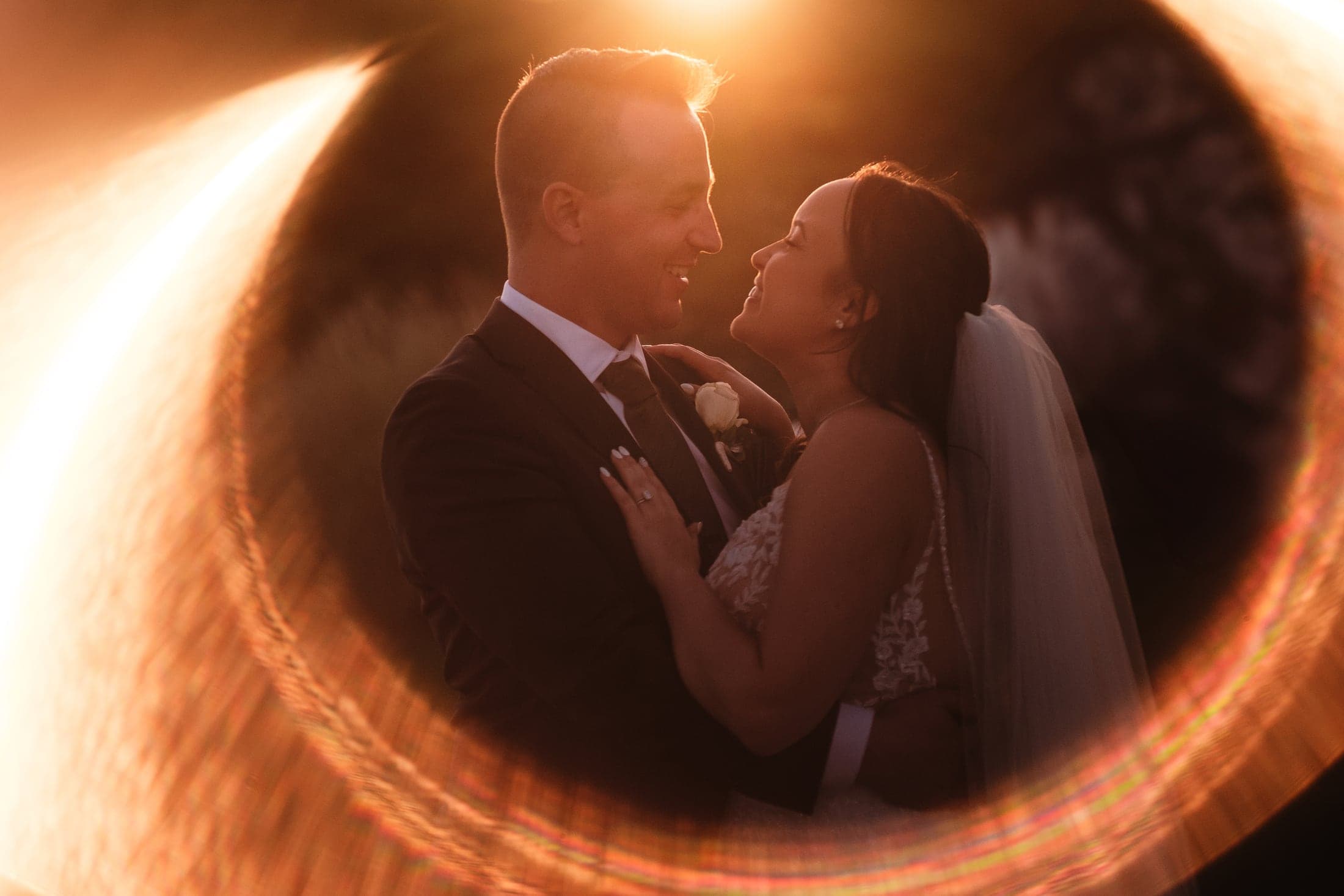 A newlywed couple smiling together through a warm ring of light