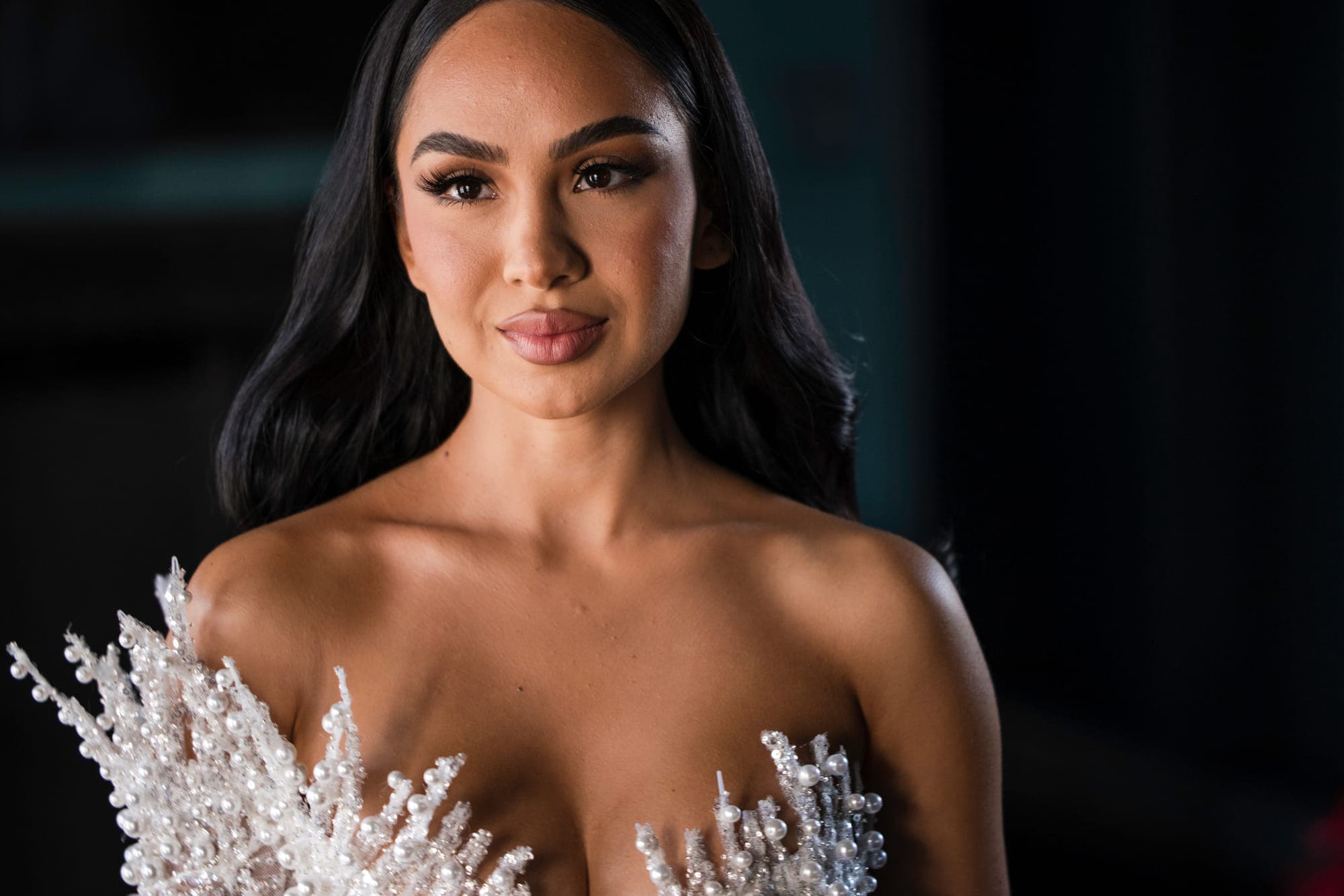 a bride in a beaded gown against a dark background, straight out of camera
