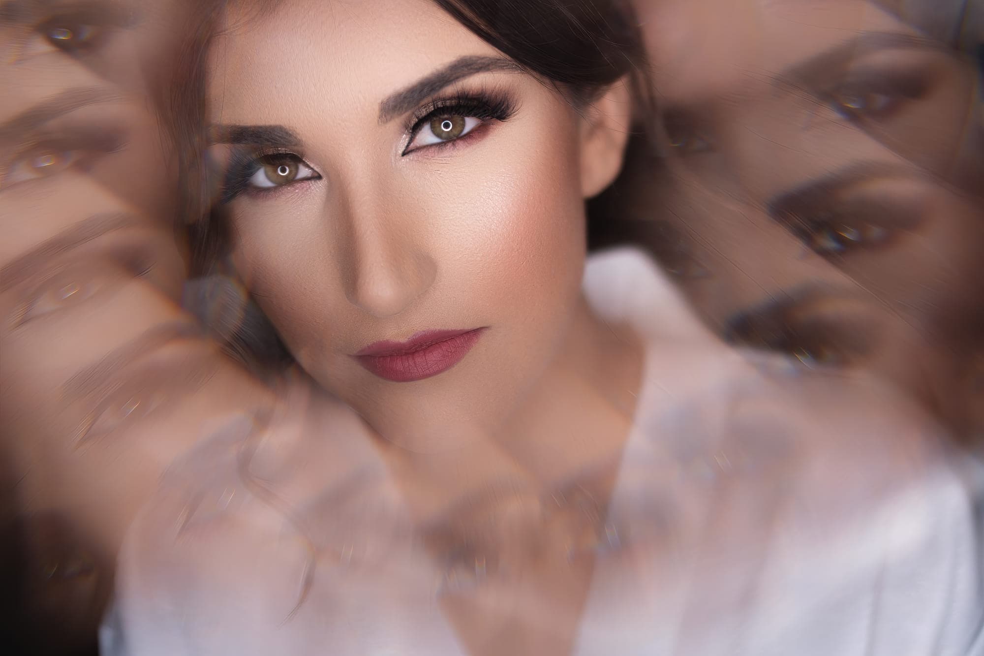 a bride photographed through a veil, her reflection repeating around her, after retouching