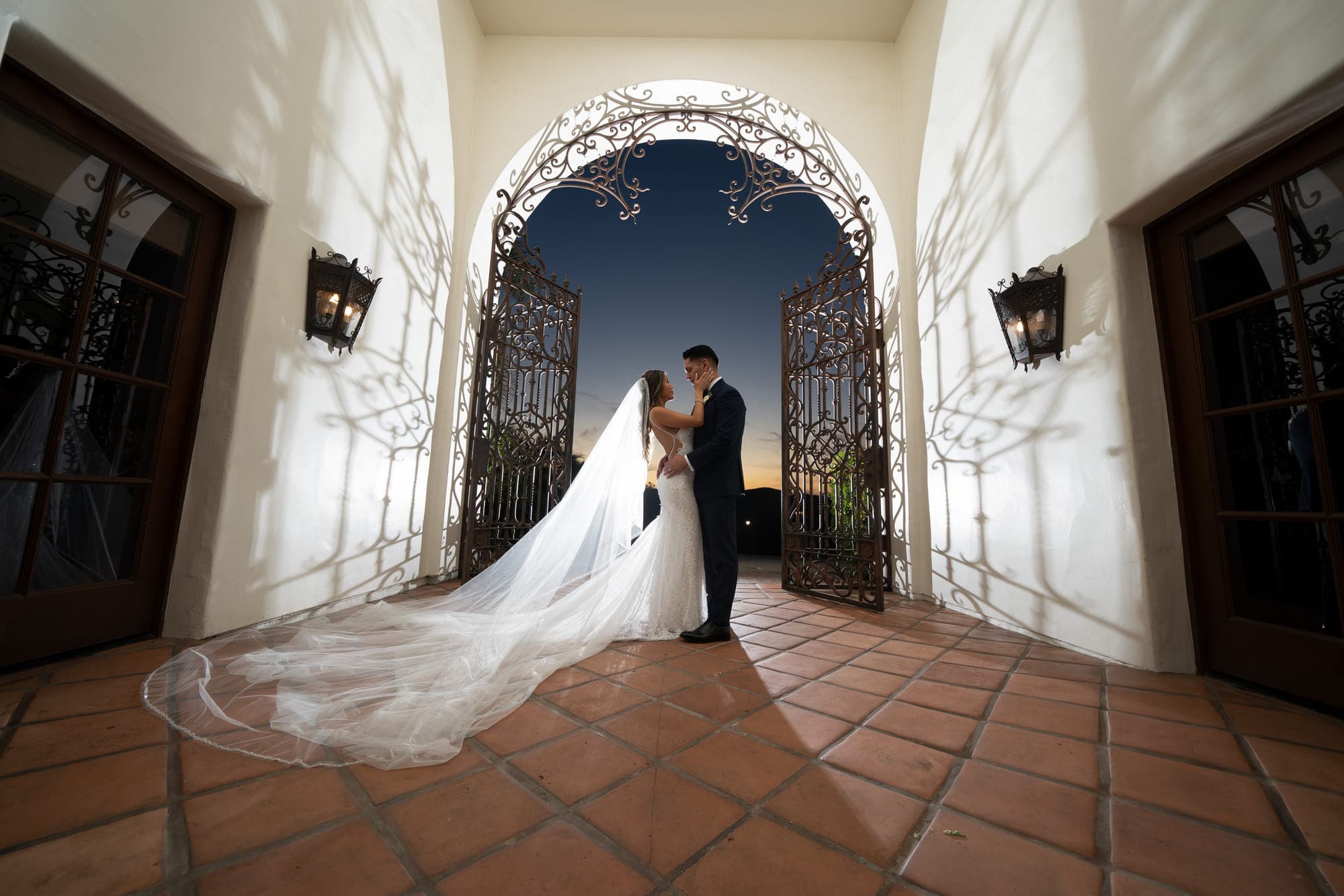 a bride and groom in a Spanish archway with a cathedral veil across the tile, straight out of camera
