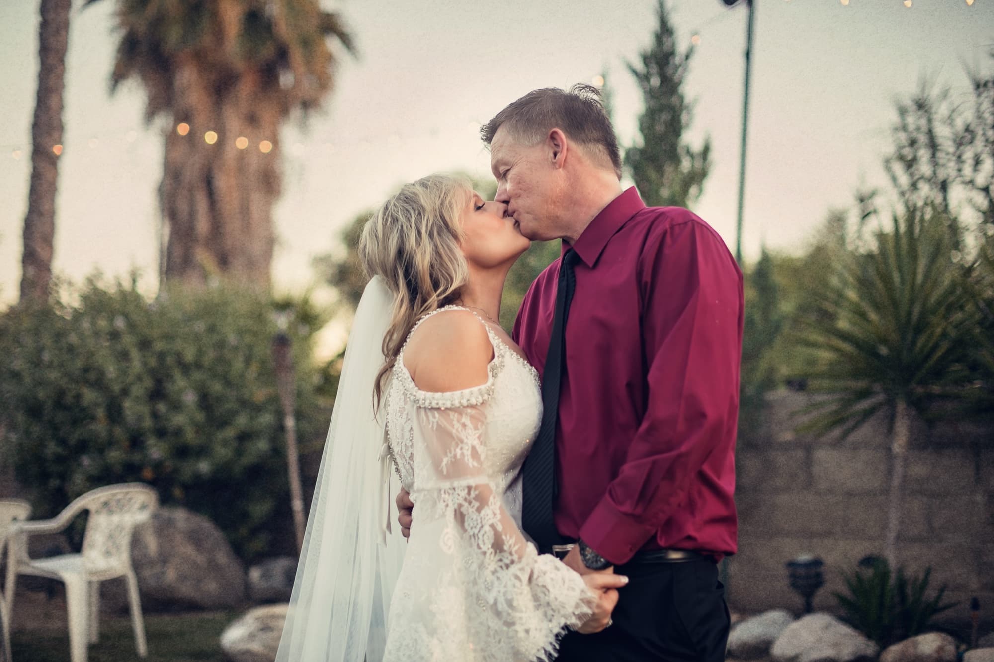 Sheridi and Greg kissing beneath the palms in the last light of their wedding day at 40 Palms Estates