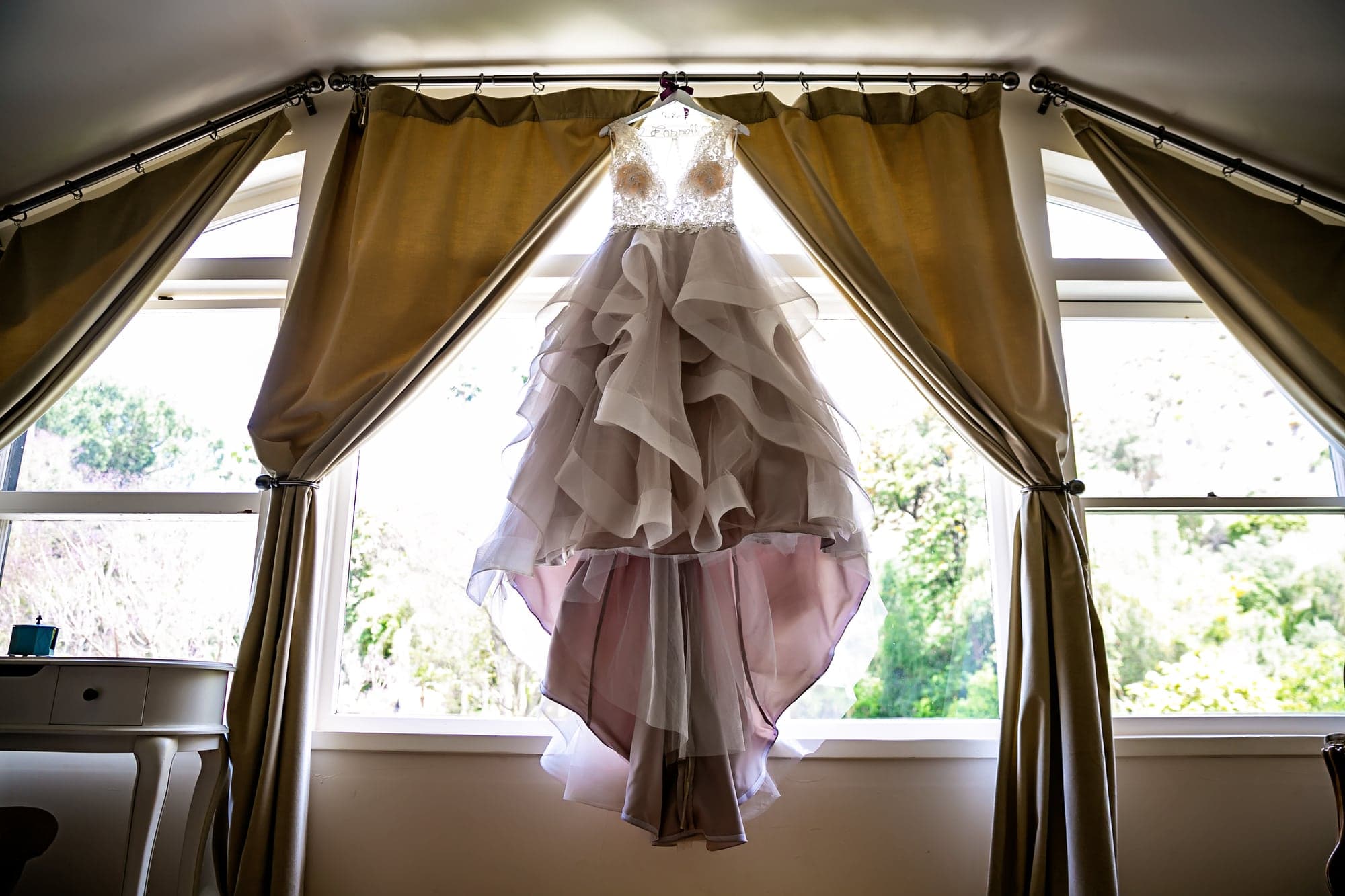 Layered wedding dress hanging in a Victorian room
