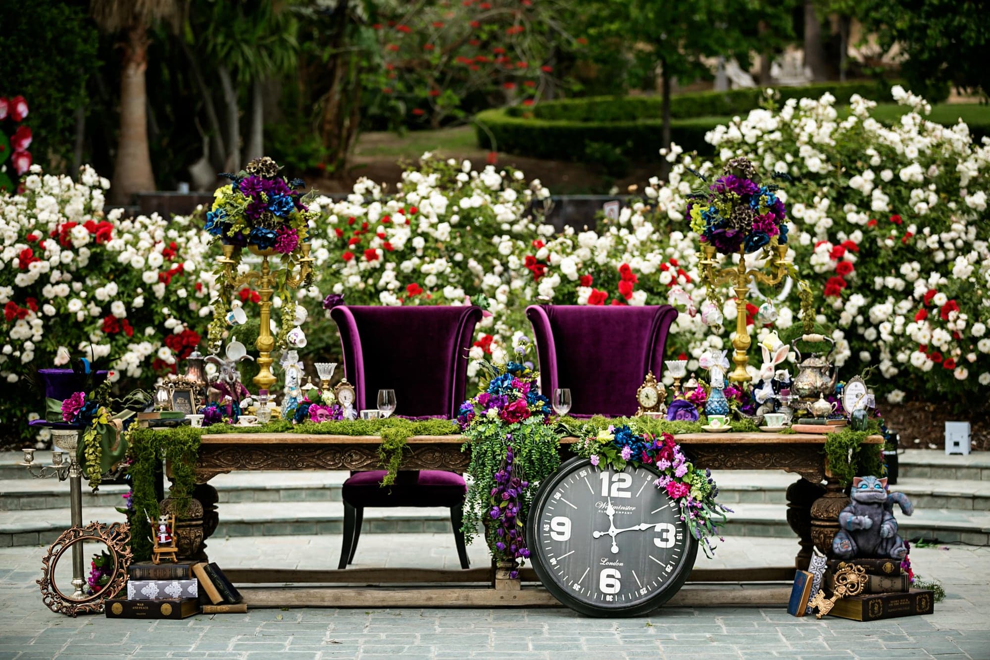 Whimsical ceremony table decorated with flowers and clocks
