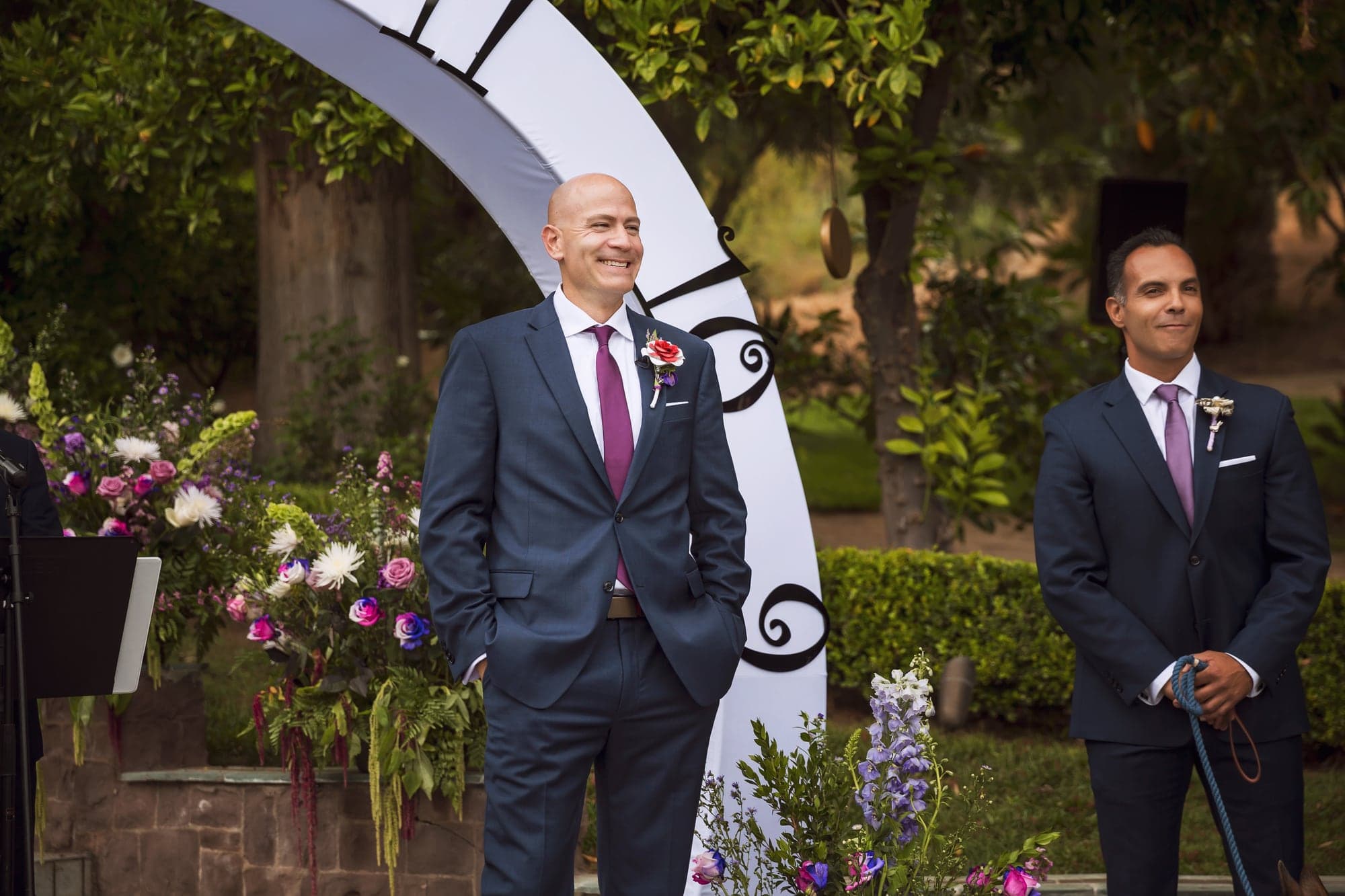 Groom waiting beneath a clock-inspired ceremony arch