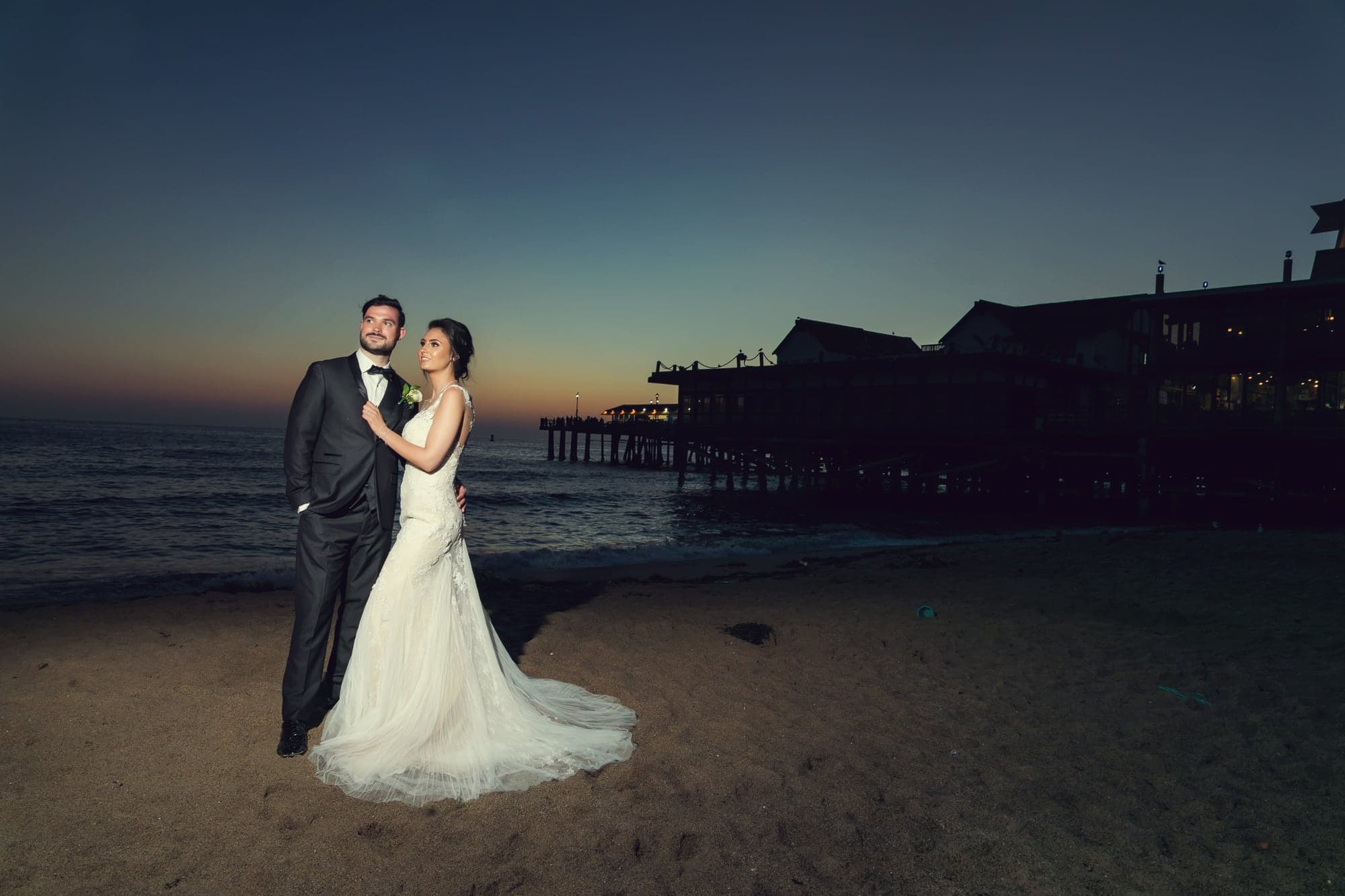 Tamara and Kevin standing beside the Redondo Beach pier after sunset