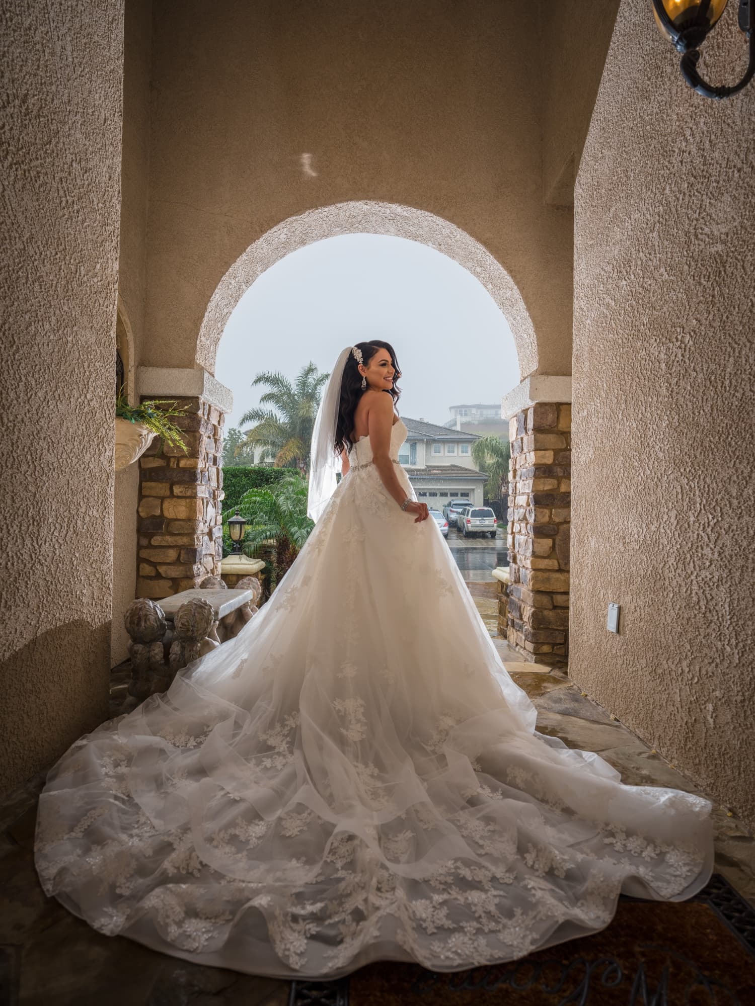 Margaret looking back over her shoulder in a stone archway, her couture ballgown train fanned across the floor, photographed by Michael Anthony Photography
