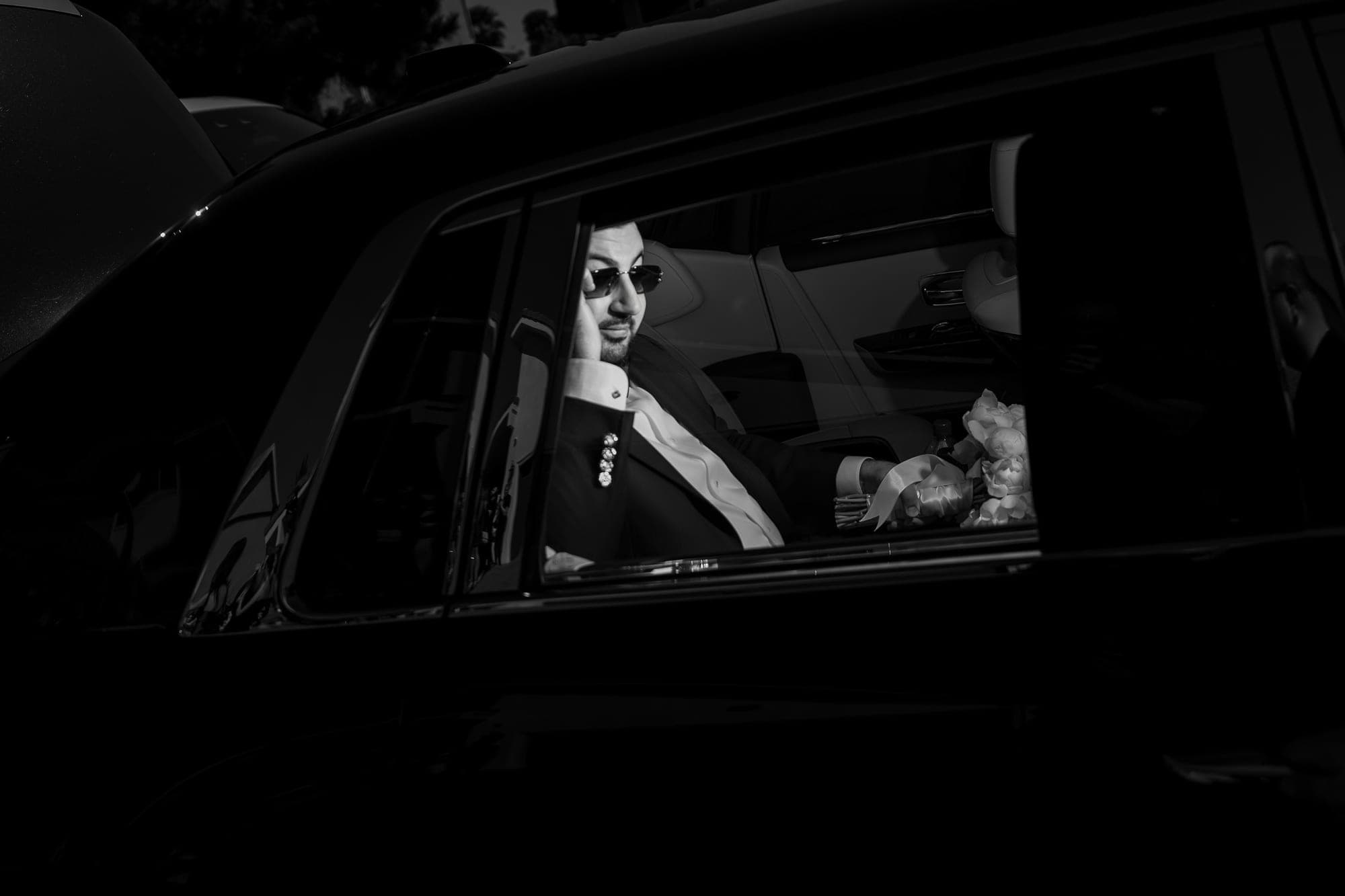 Black and white photograph of the bride framed in a car window on the way to the church