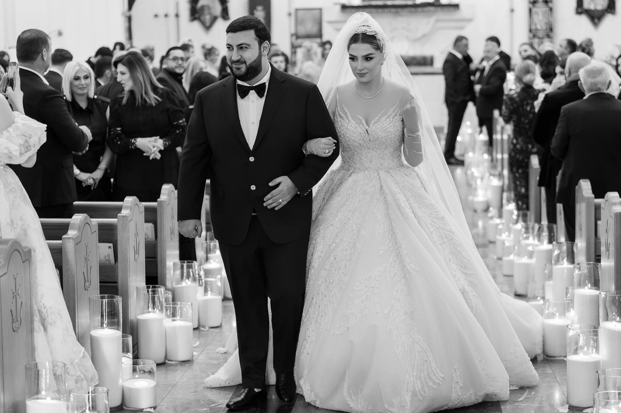 Black and white photograph of the newlyweds walking back down the candlelit aisle