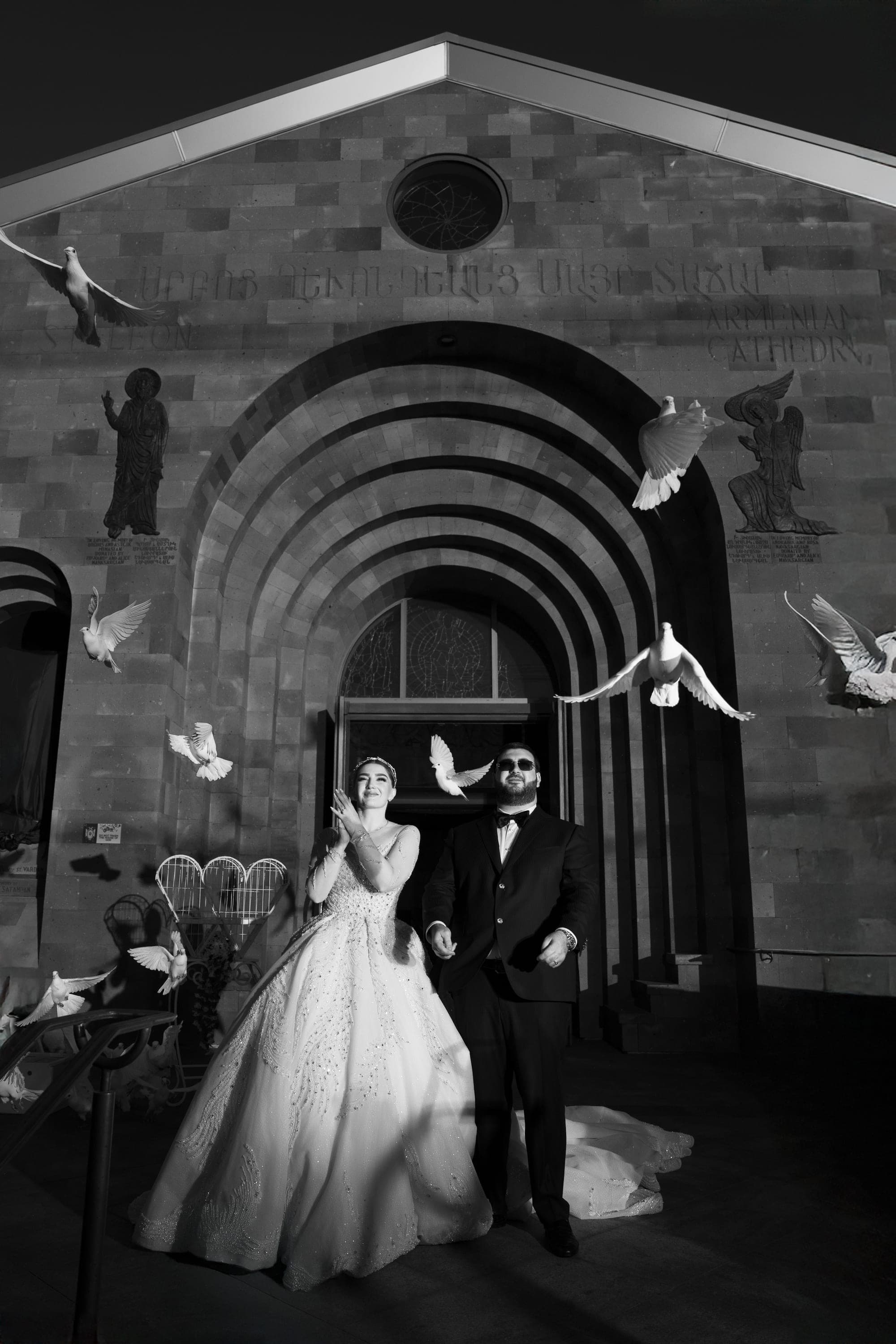 White doves released around the bride and groom in the arched doorway of the church